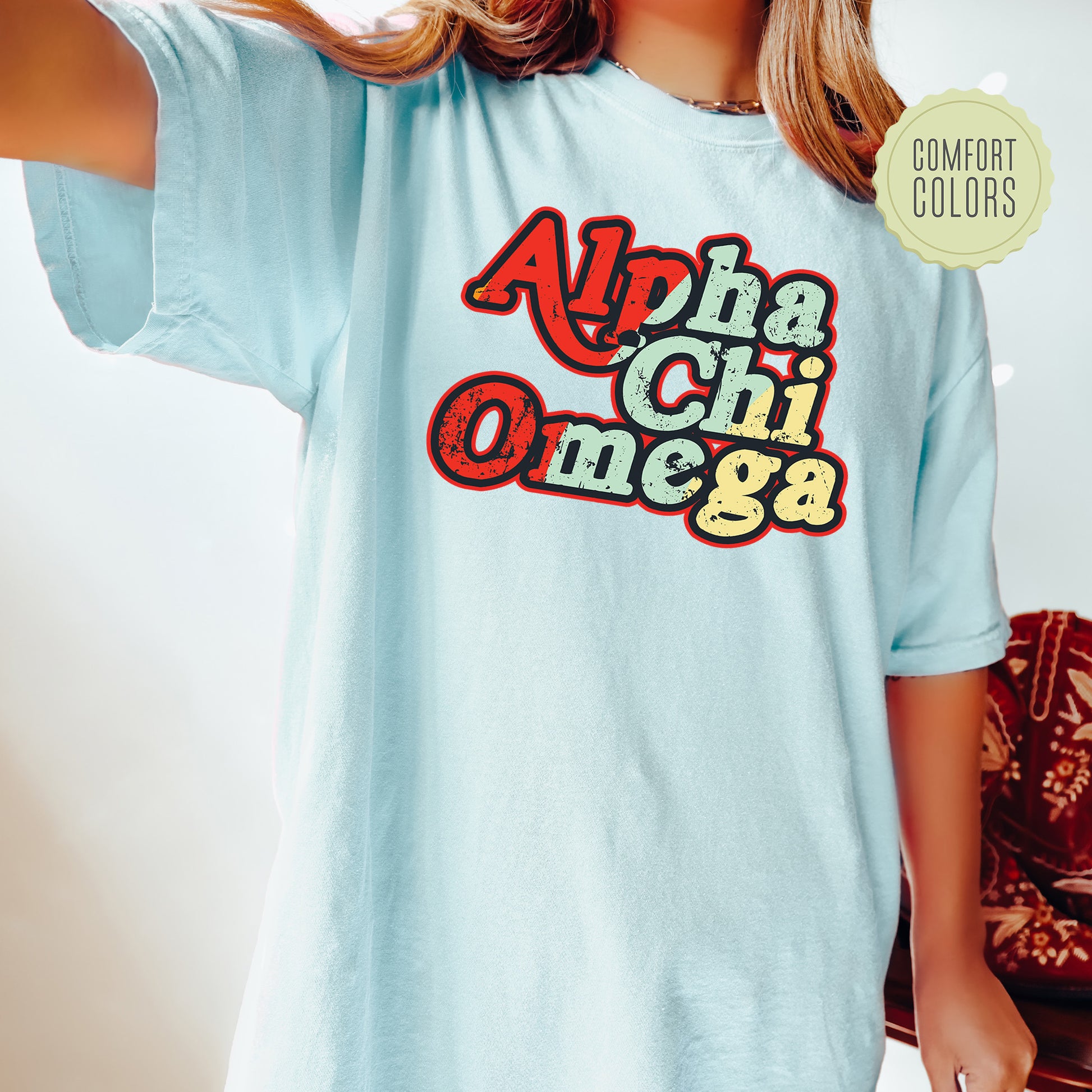 a woman wearing a light blue shirt with the words apha chii omeg