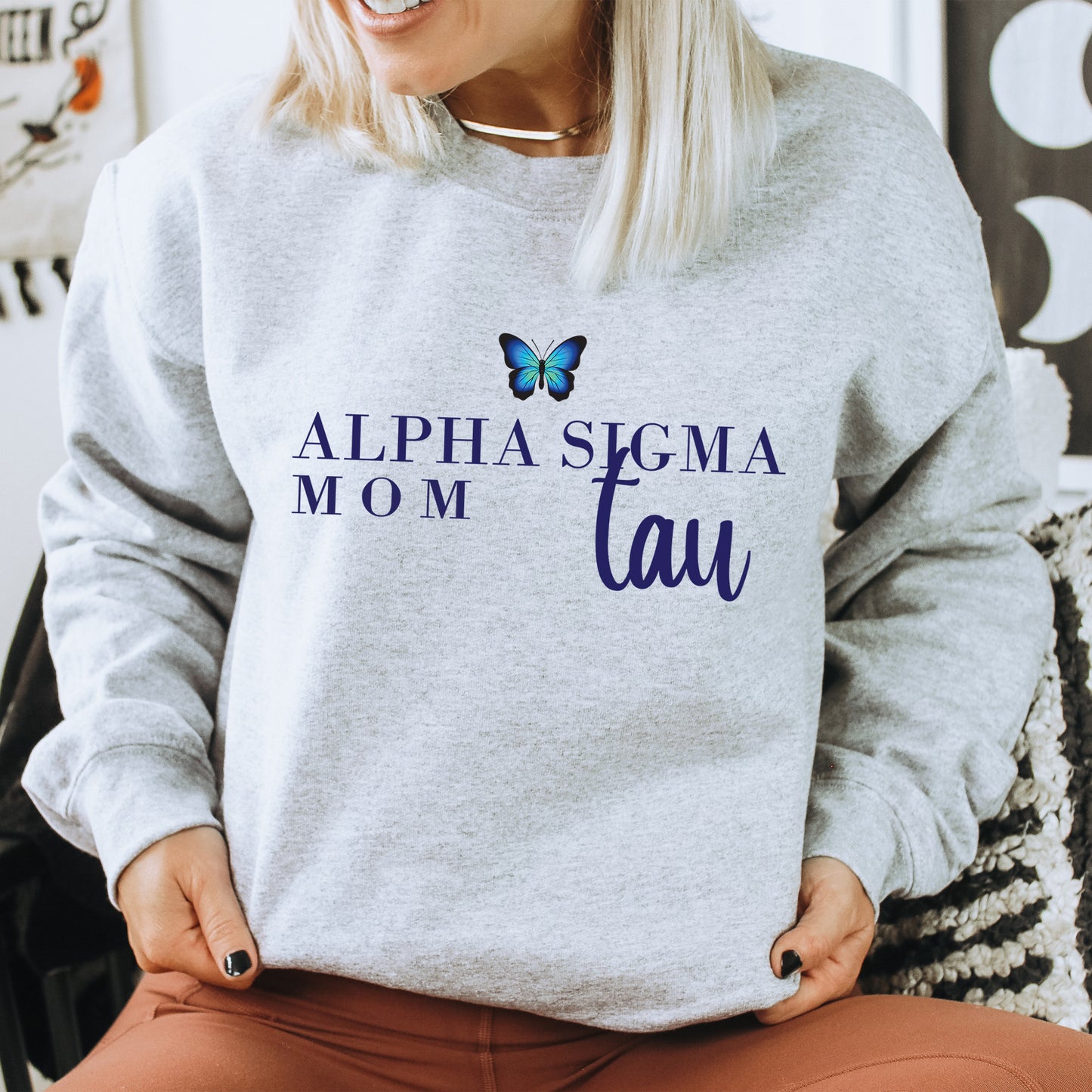 a woman sitting on a chair wearing a sweatshirt with a butterfly on it