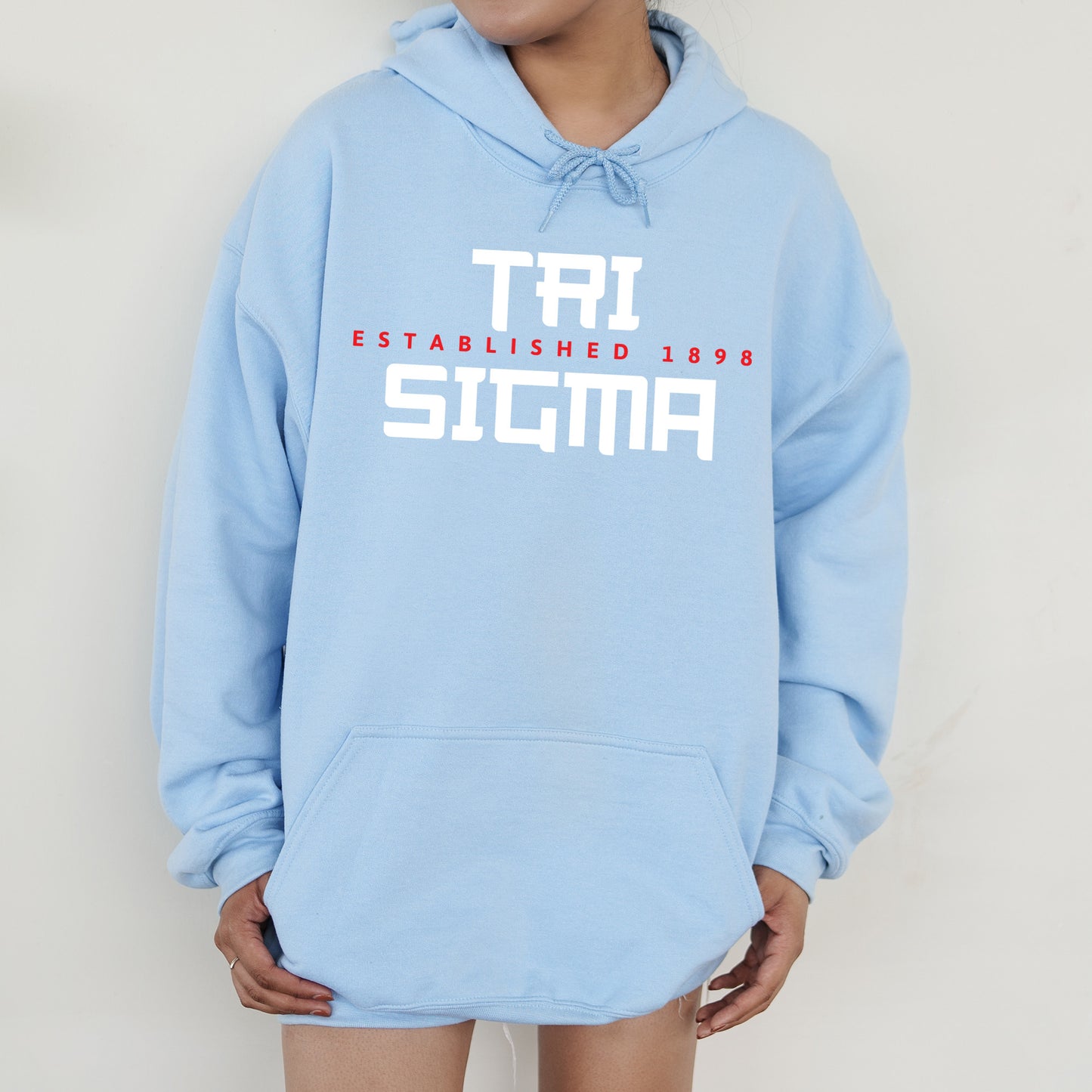a person wearing a blue hoodie with the words tri established in red and white