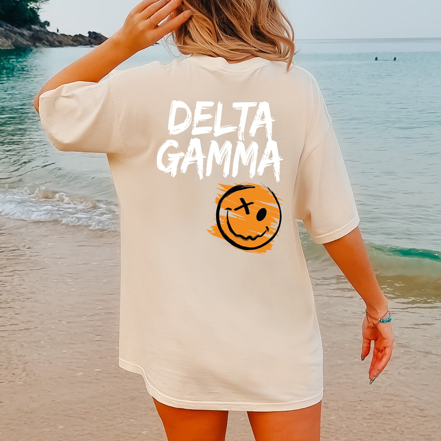 a woman standing on a beach with a smile on her shirt