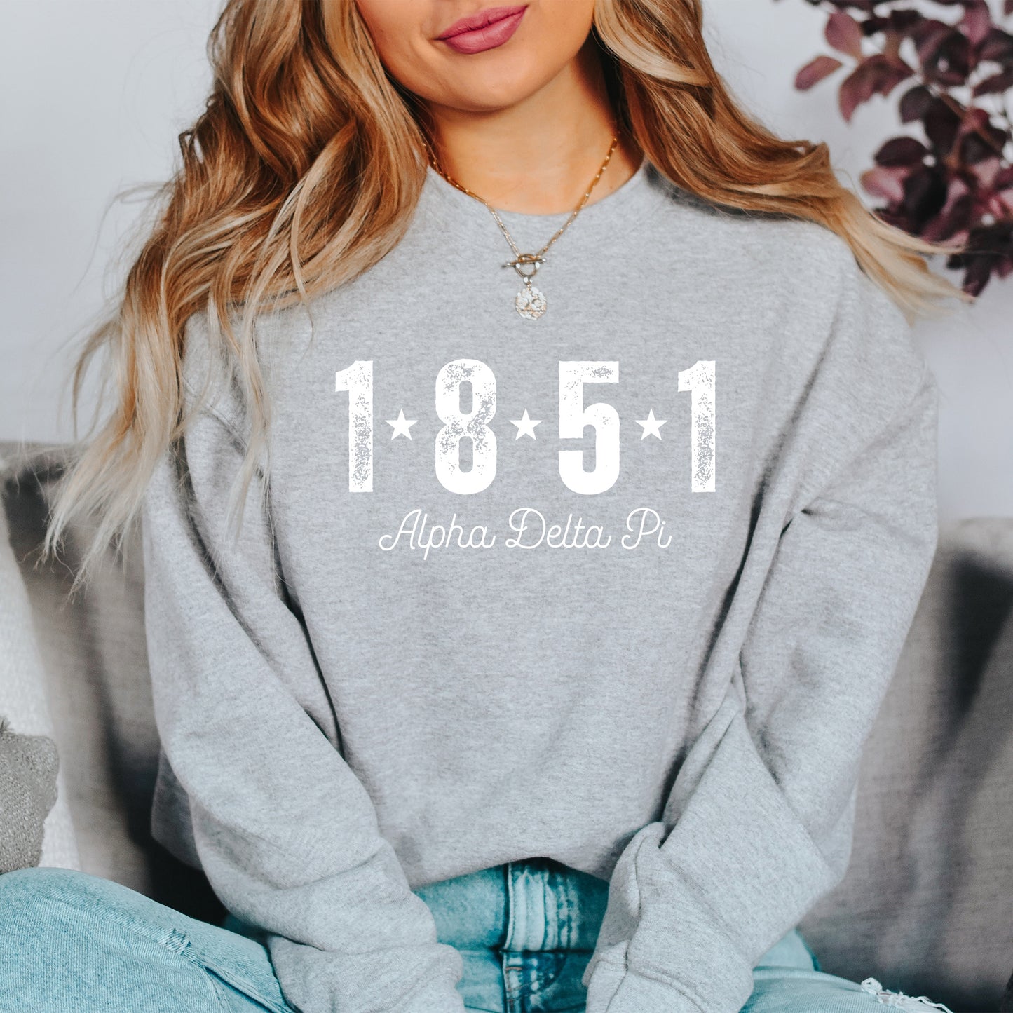 a woman sitting on a couch wearing a sweatshirt