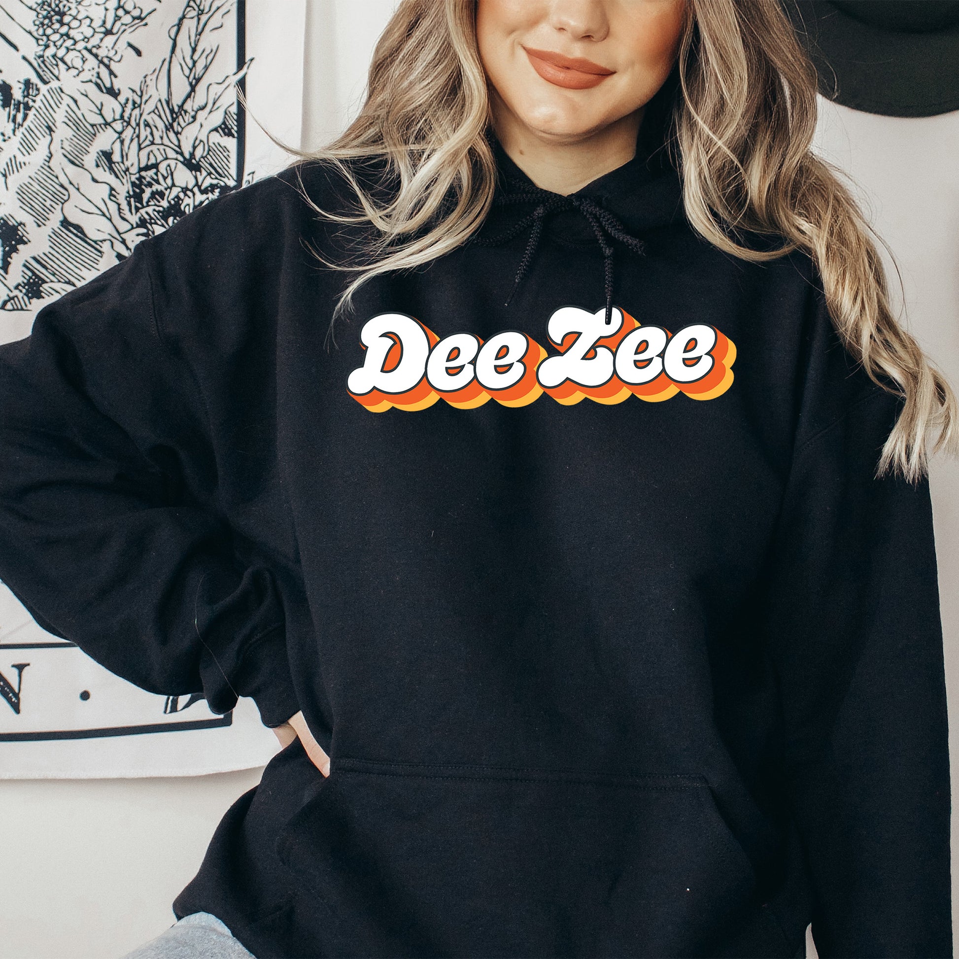 a woman wearing a black hoodie with the word dee zee on it