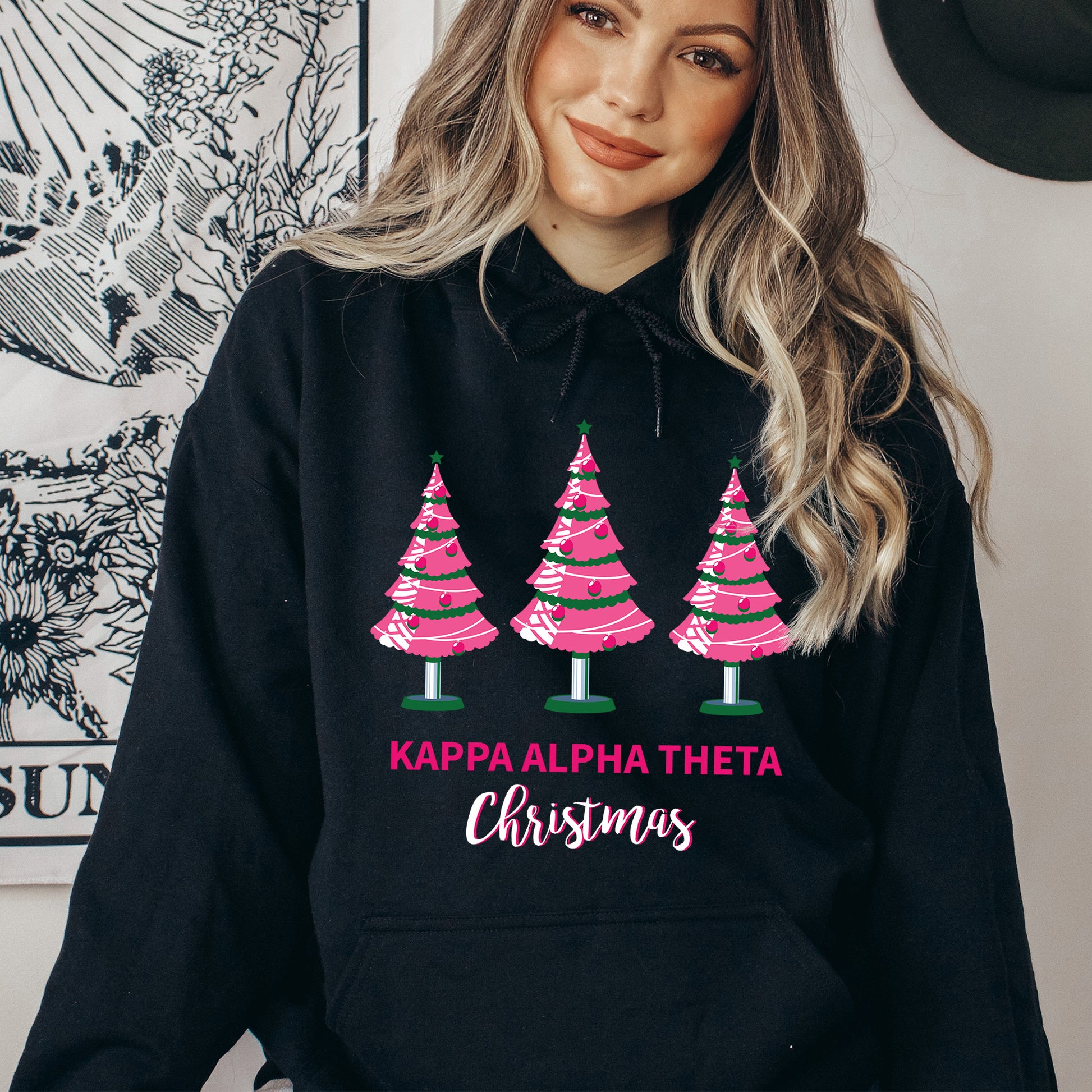a woman wearing a black hoodie with pink christmas trees on it
