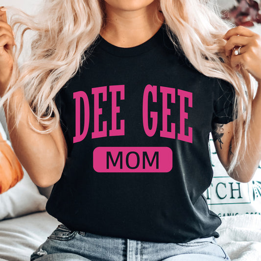 a woman sitting on a bed wearing a t - shirt that says dee gee mom