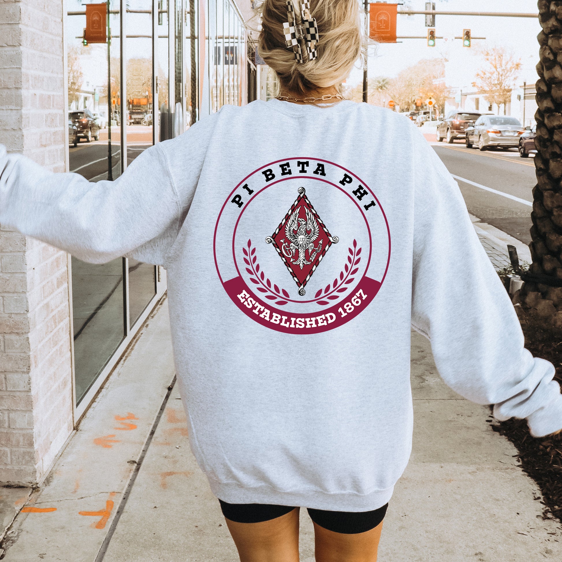 a woman walking down a sidewalk wearing a white sweatshirt