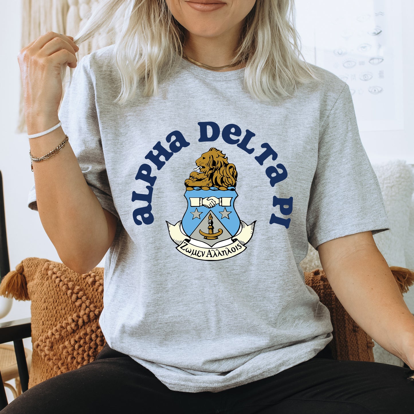a woman sitting on a chair wearing a delta delta shirt