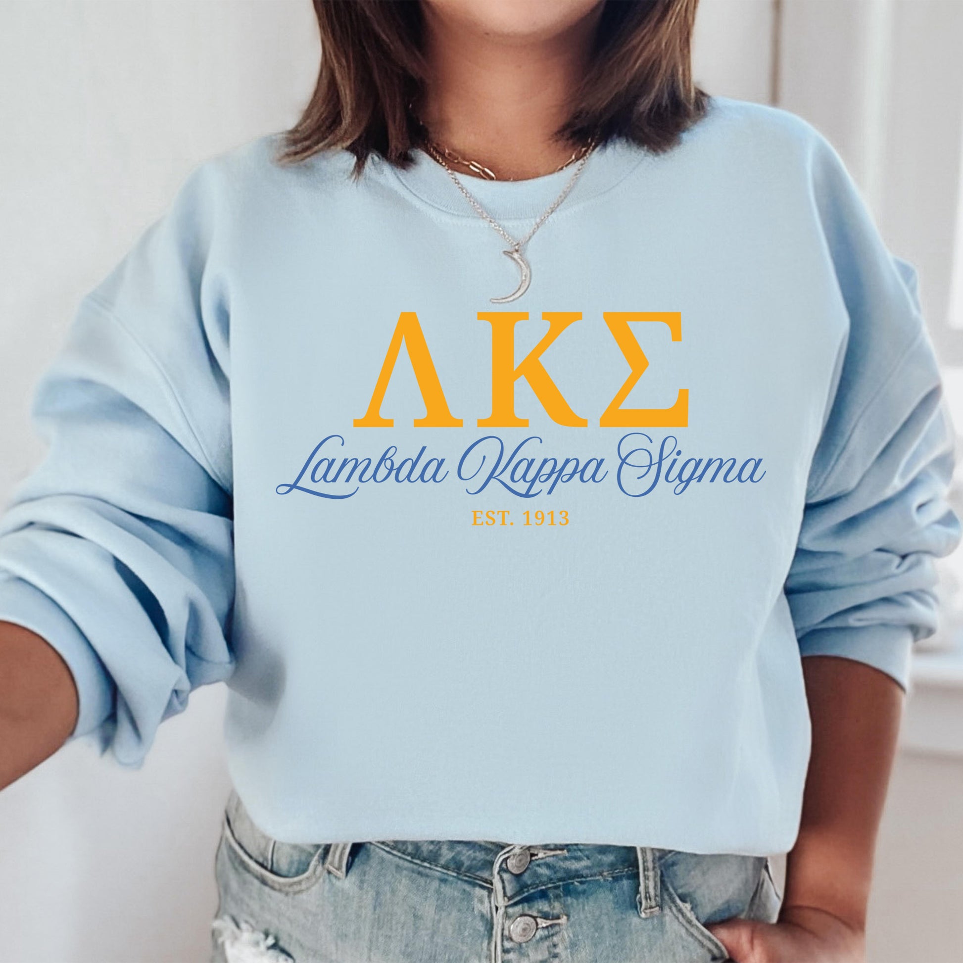 a woman wearing a light blue sweatshirt with greek letters