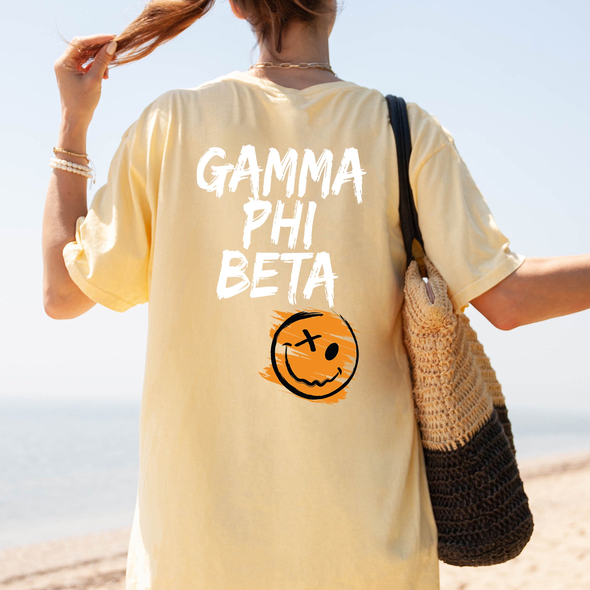 a woman walking on the beach with a smile on her shirt