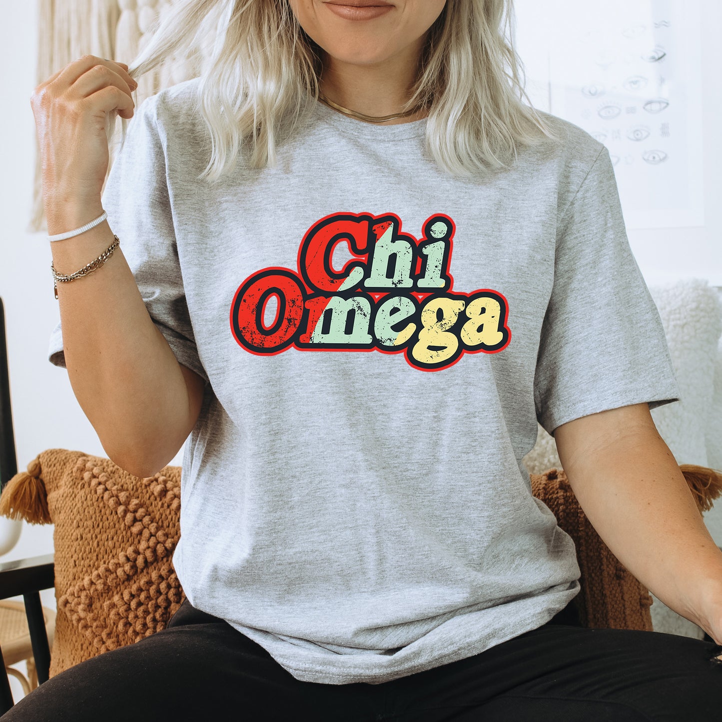 a woman sitting on a chair wearing a t - shirt that says chi omega