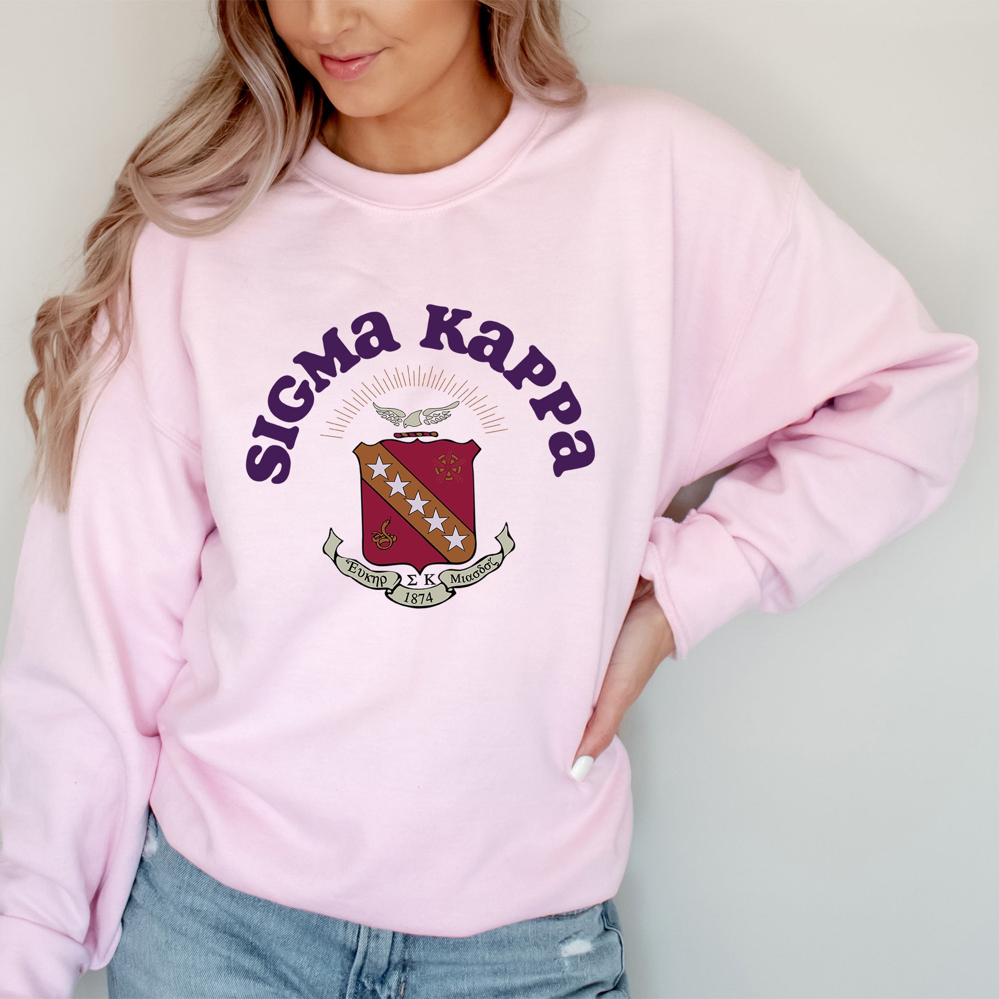 a woman wearing a pink sweatshirt with a crest on it