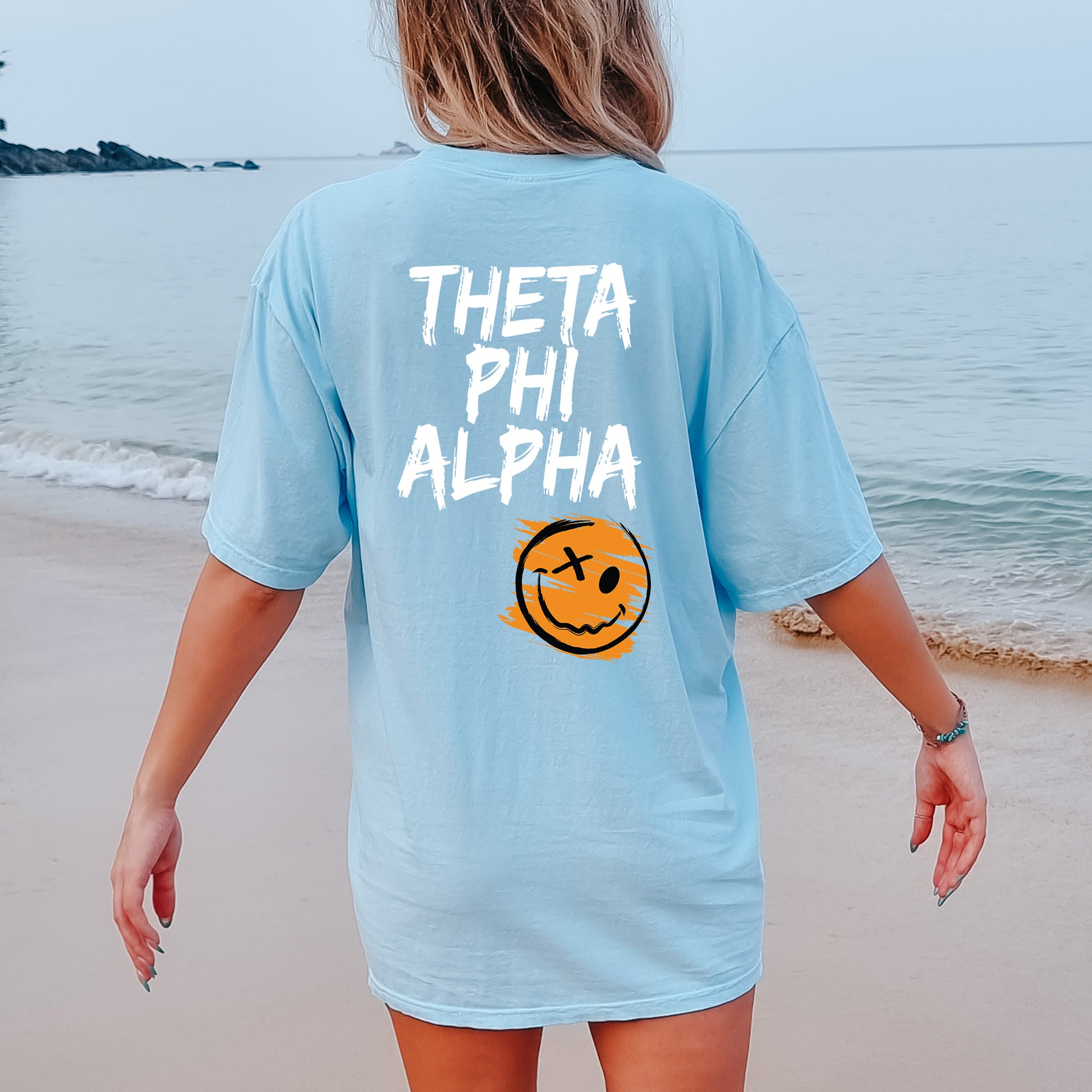a woman walking on the beach with a smile on her shirt