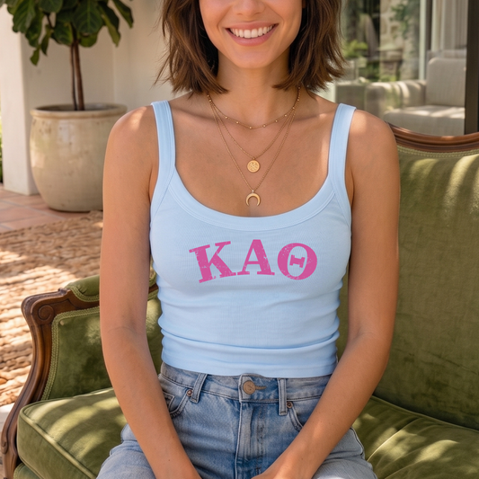 A woman wearing a light blue tank top with pink text and jeans is sitting on a green couch.