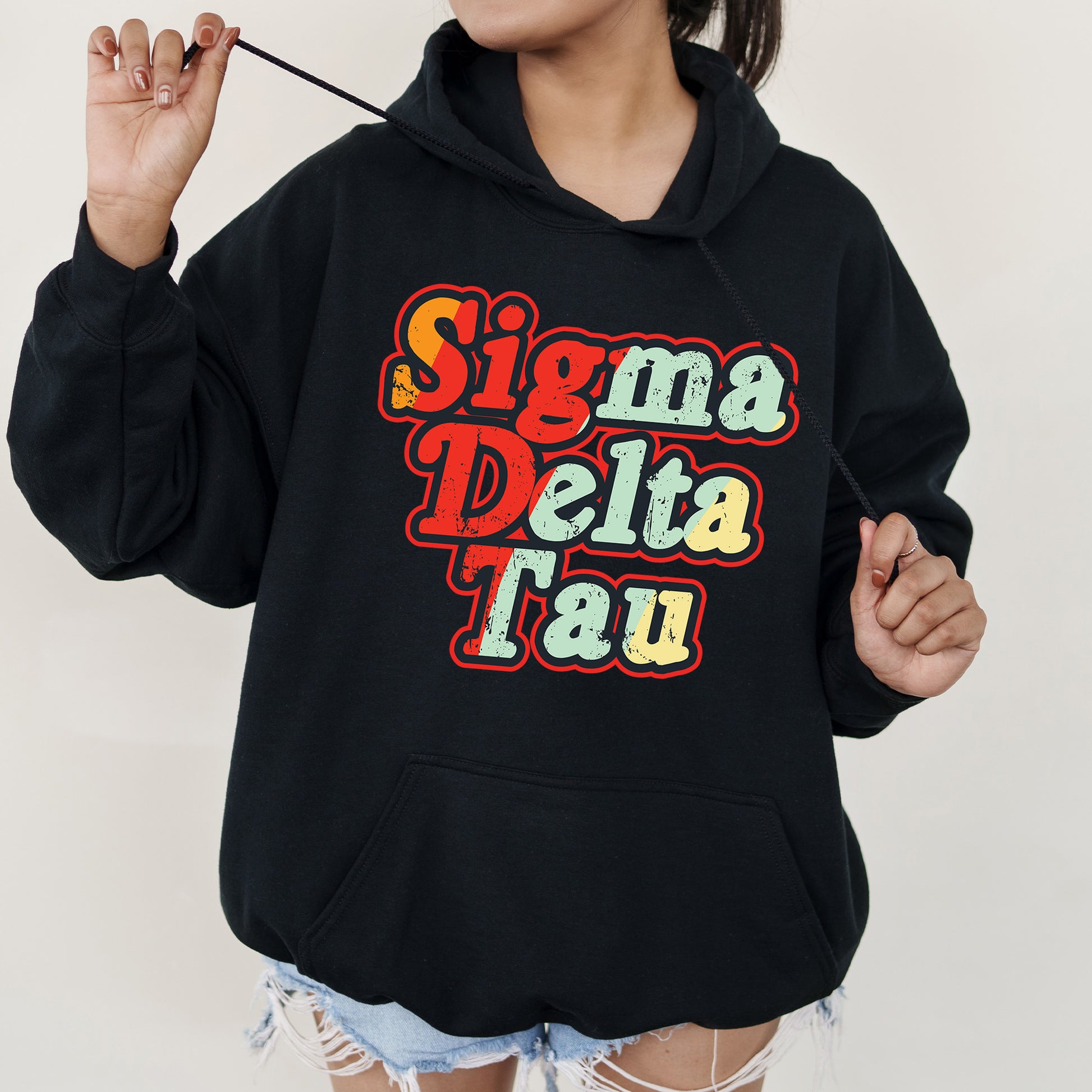 a woman wearing a black hoodie with the words stigma delta tau on it