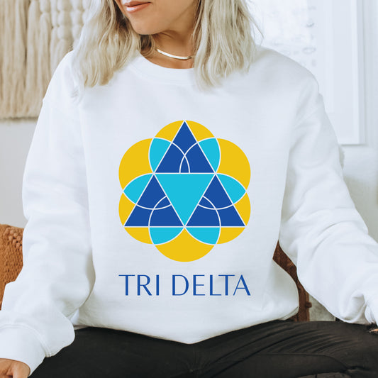 a woman sitting on a couch wearing a white sweatshirt with the tri delta logo on