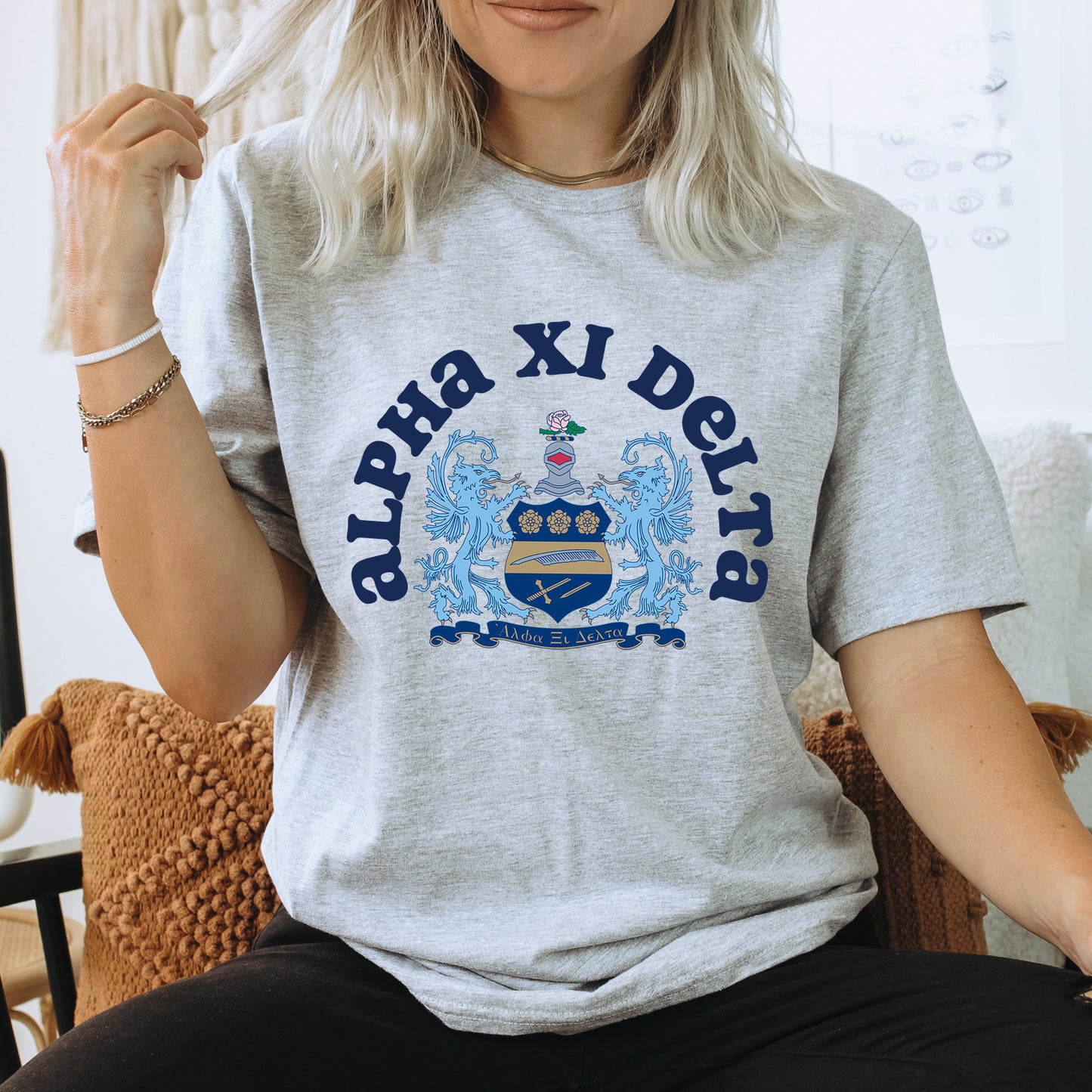 a woman sitting on a chair wearing a shirt with a coat of arms on it