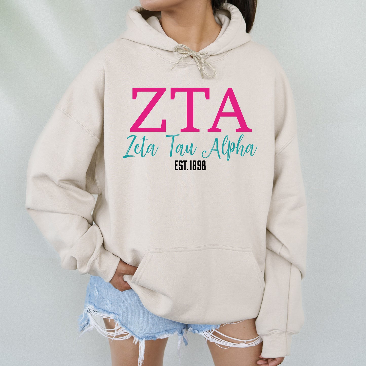 a woman wearing a white hoodie with a pink zta on it