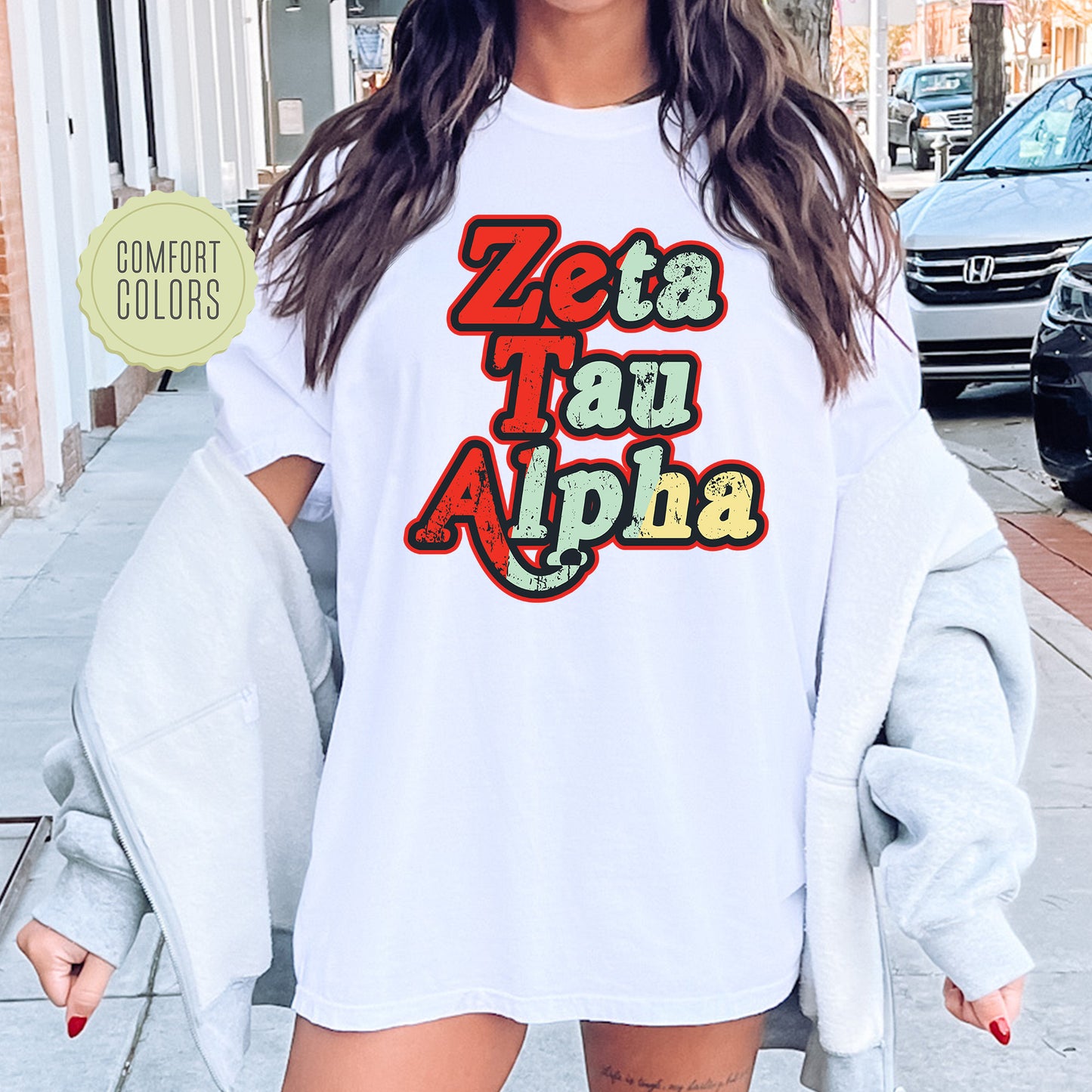 a woman wearing a white shirt with the words zeta tau alpha on it