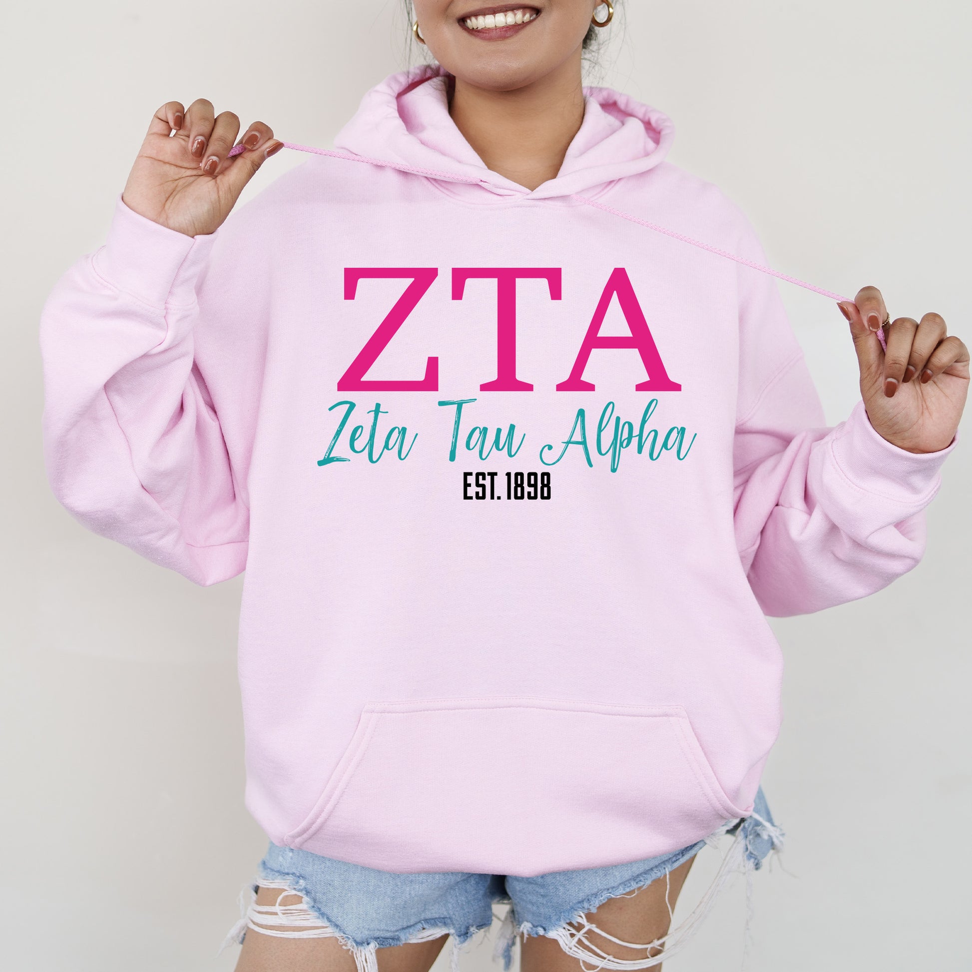 a woman wearing a pink hoodie with the letters zta on it