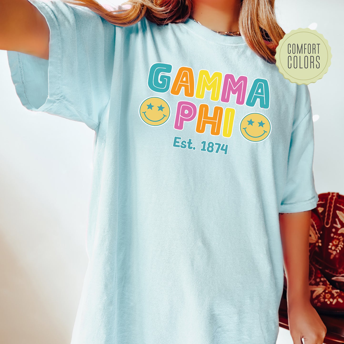 a woman wearing a light blue shirt with the words gama phi on it