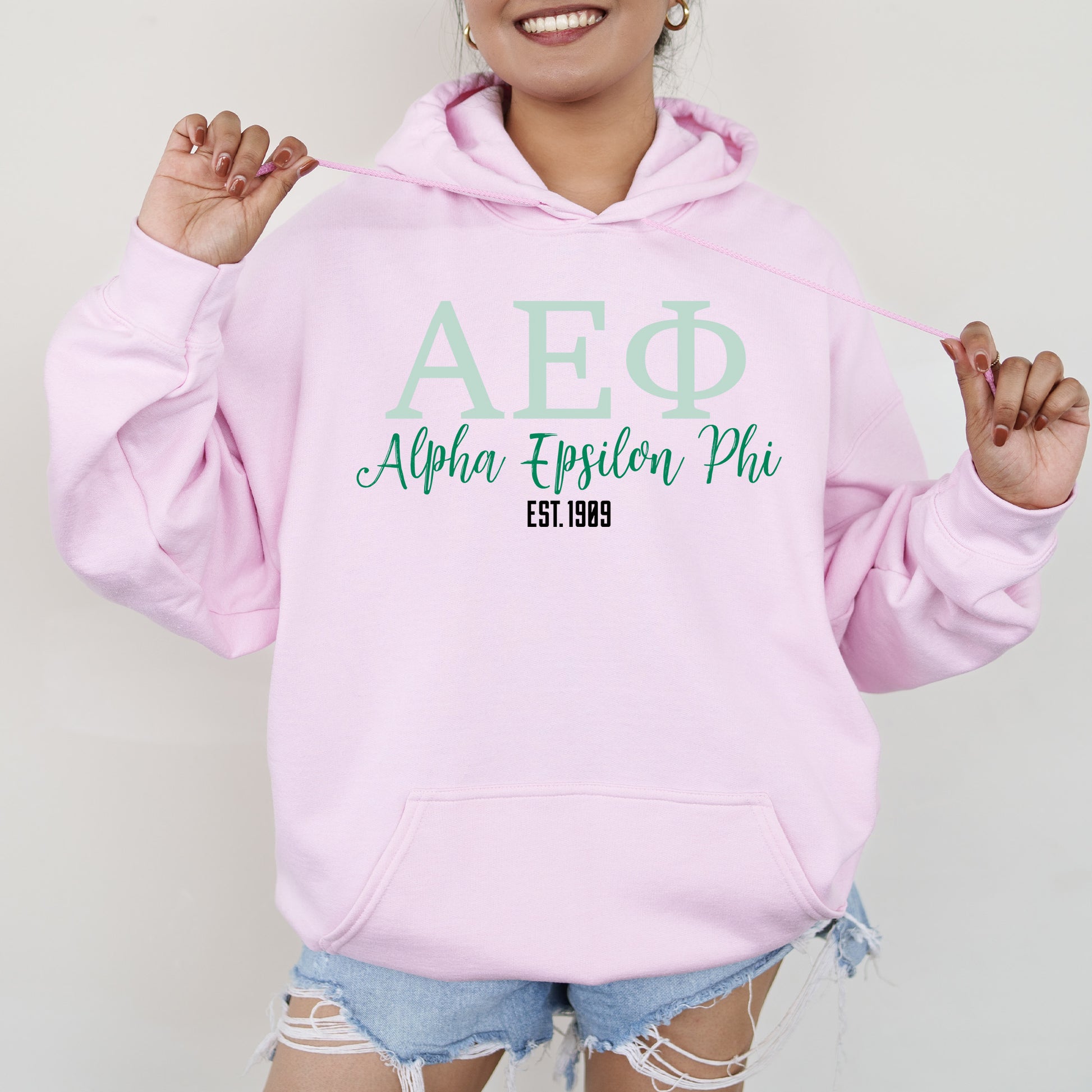 a woman wearing a pink hoodie and ripped shorts