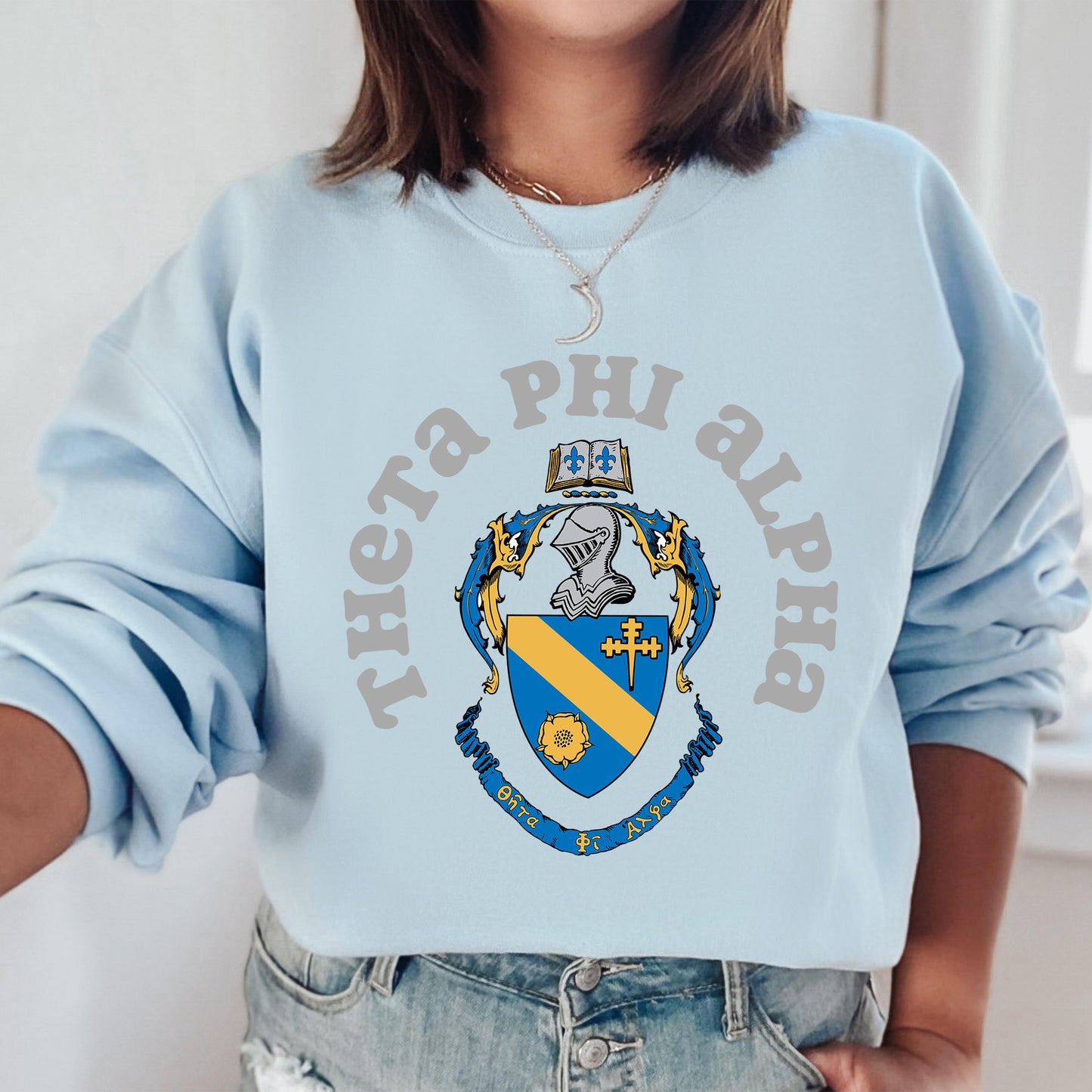 a woman wearing a light blue phi phi sweatshirt