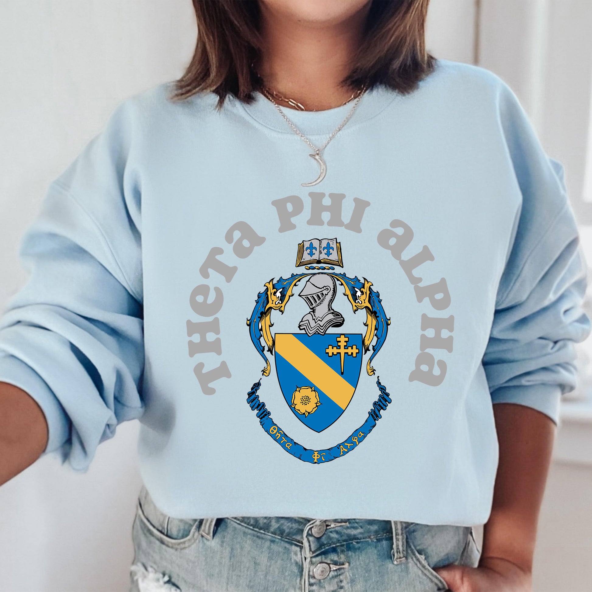 a woman wearing a light blue phi phi sweatshirt