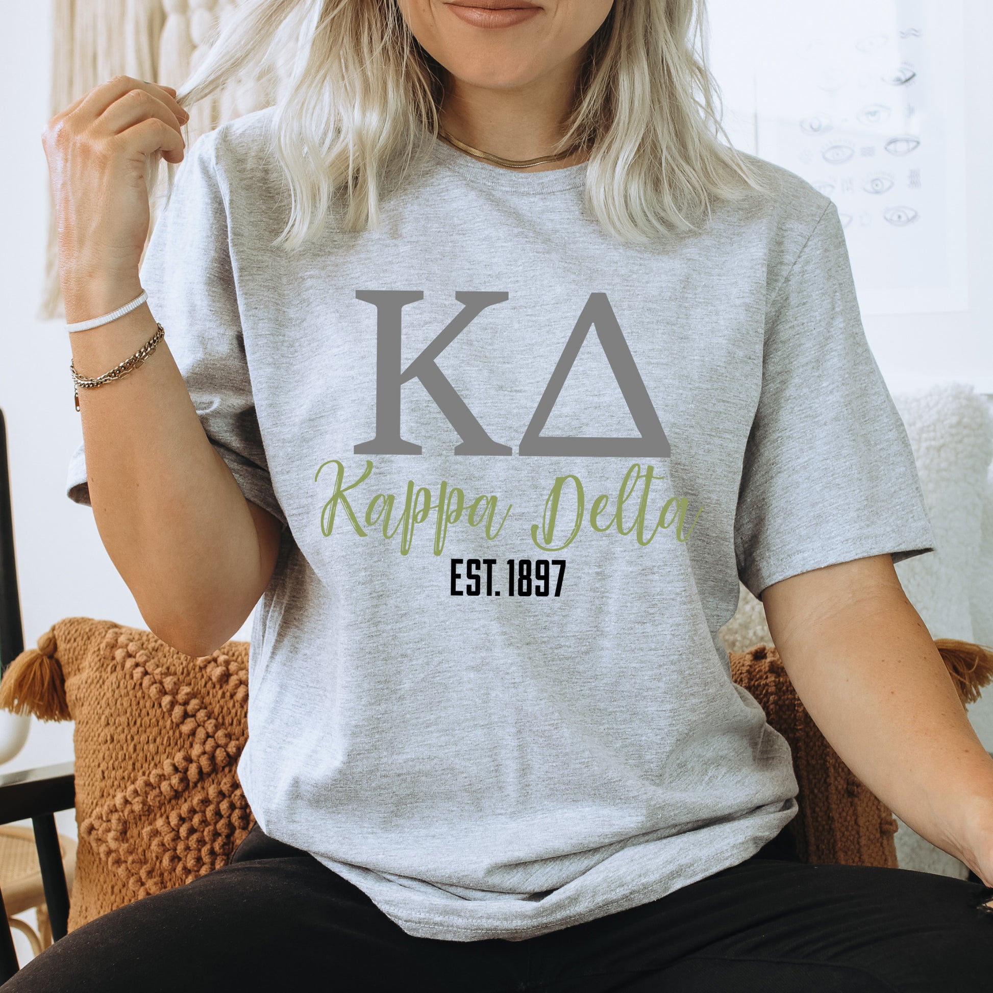 a woman sitting on a chair wearing a t - shirt that says ka happy delta