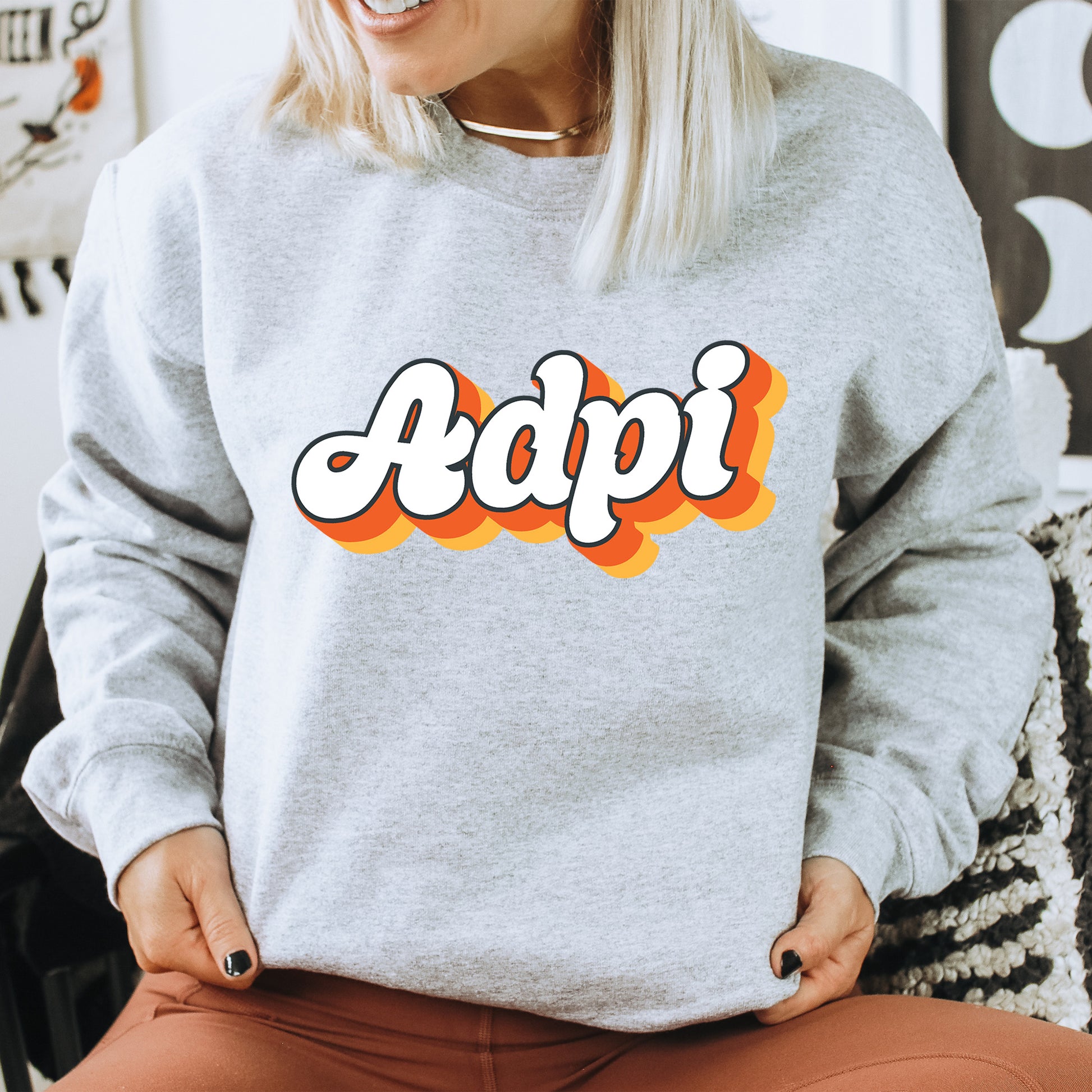 a woman sitting on a chair wearing a sweatshirt with the word appi printed on