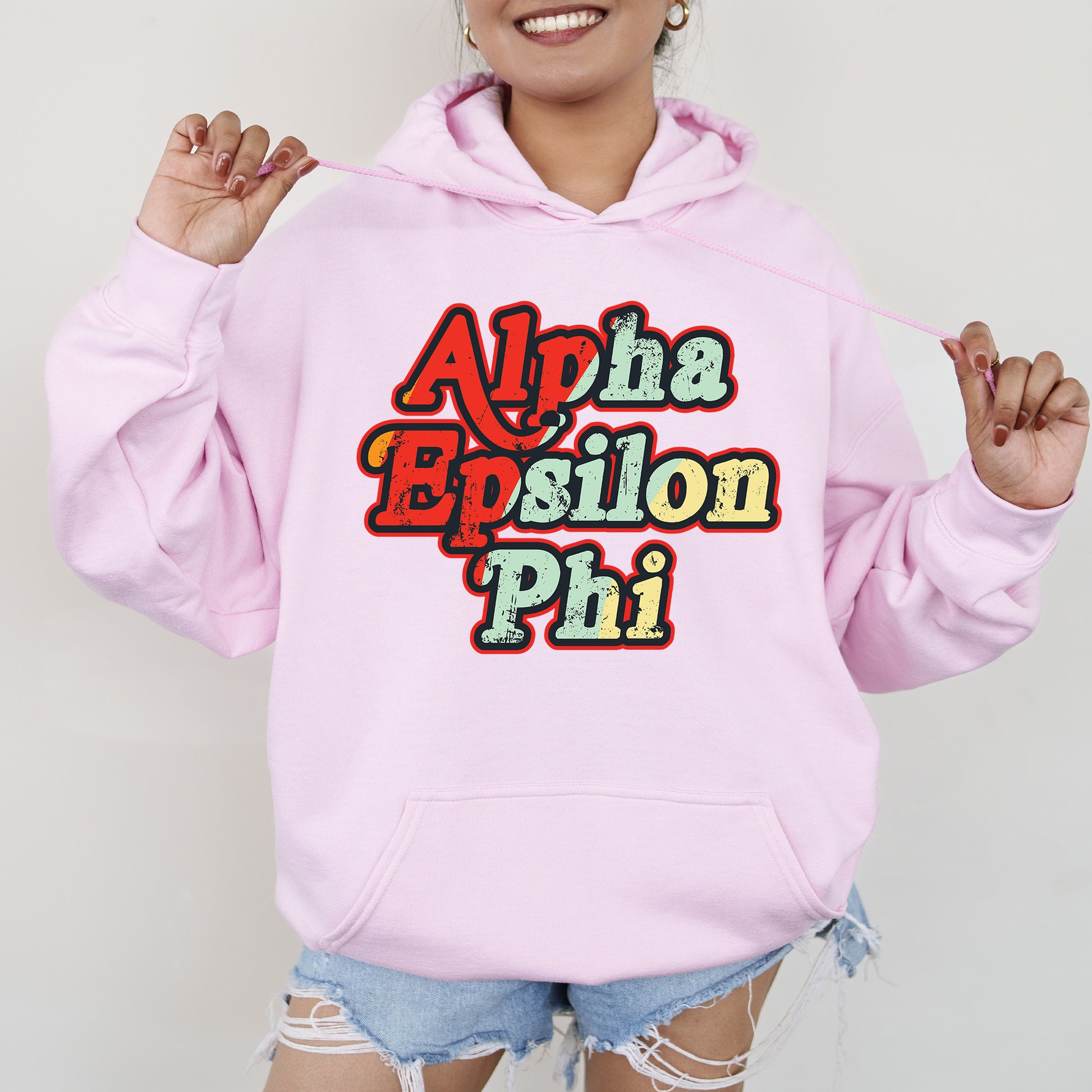 a woman wearing a pink hoodie with the words aloha epsilon