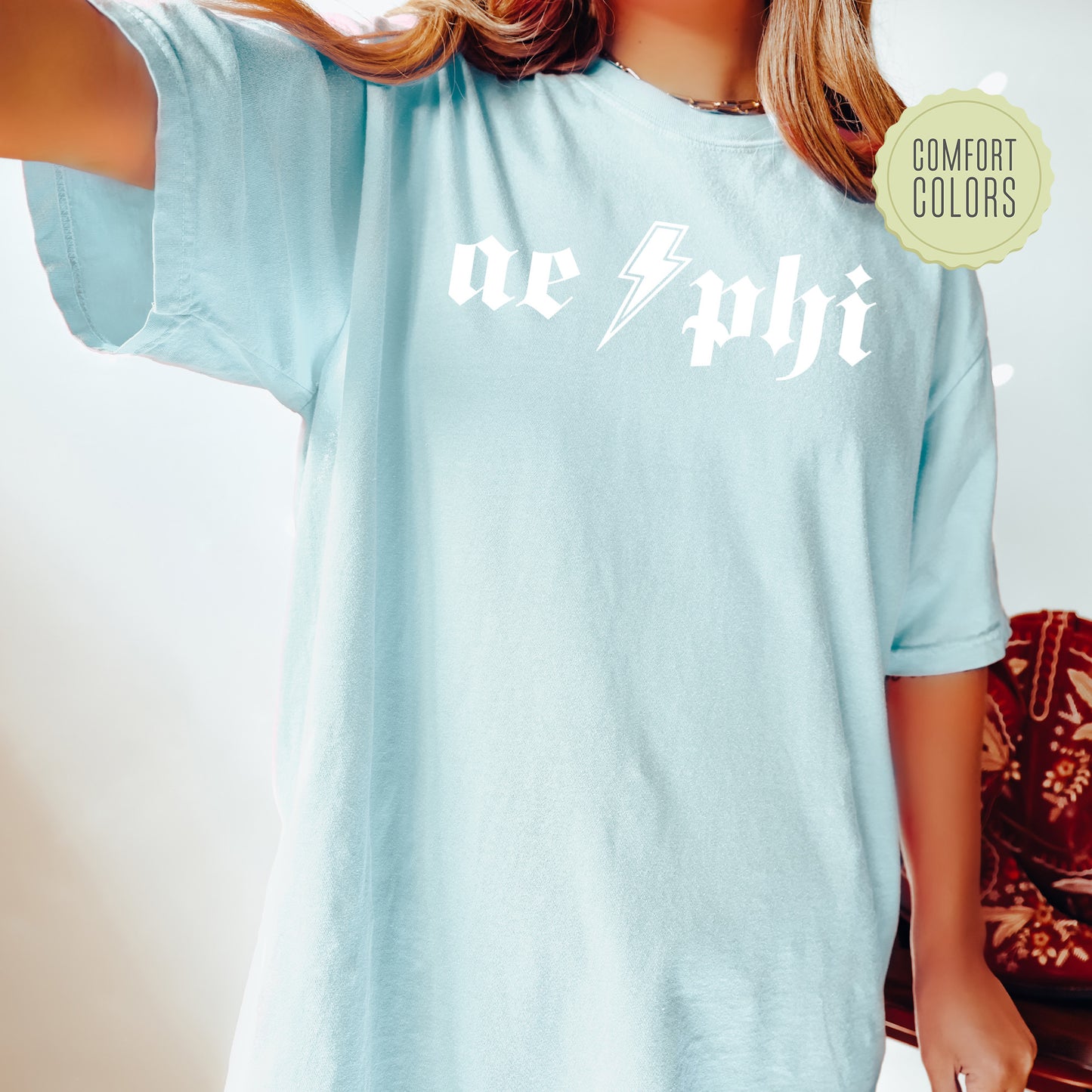 a woman wearing a light blue shirt with the word achi printed on it
