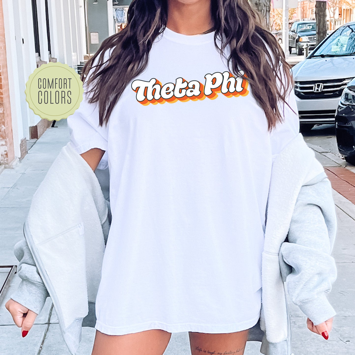 a woman wearing a white shirt with the words thea phi on it