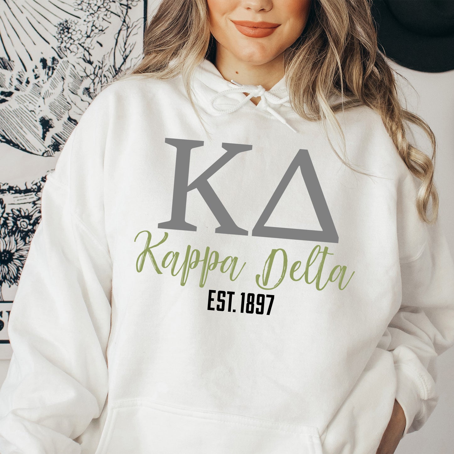 a woman wearing a white hoodie with the letters kalppa delta on it