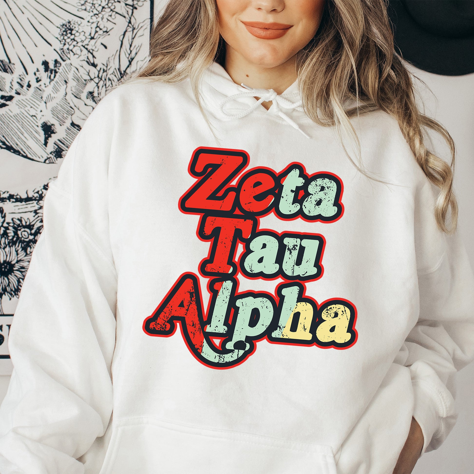 a woman wearing a white hoodie that says zeba tau alpha