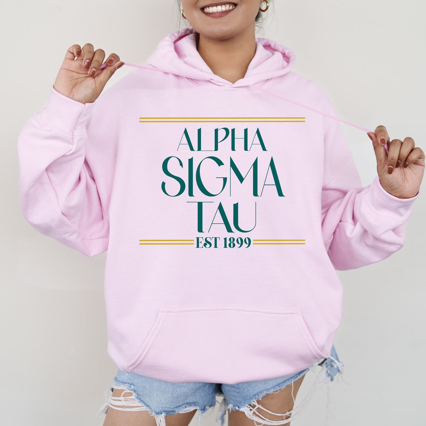 a woman wearing a pink hoodie with the words, alpha sigma tau