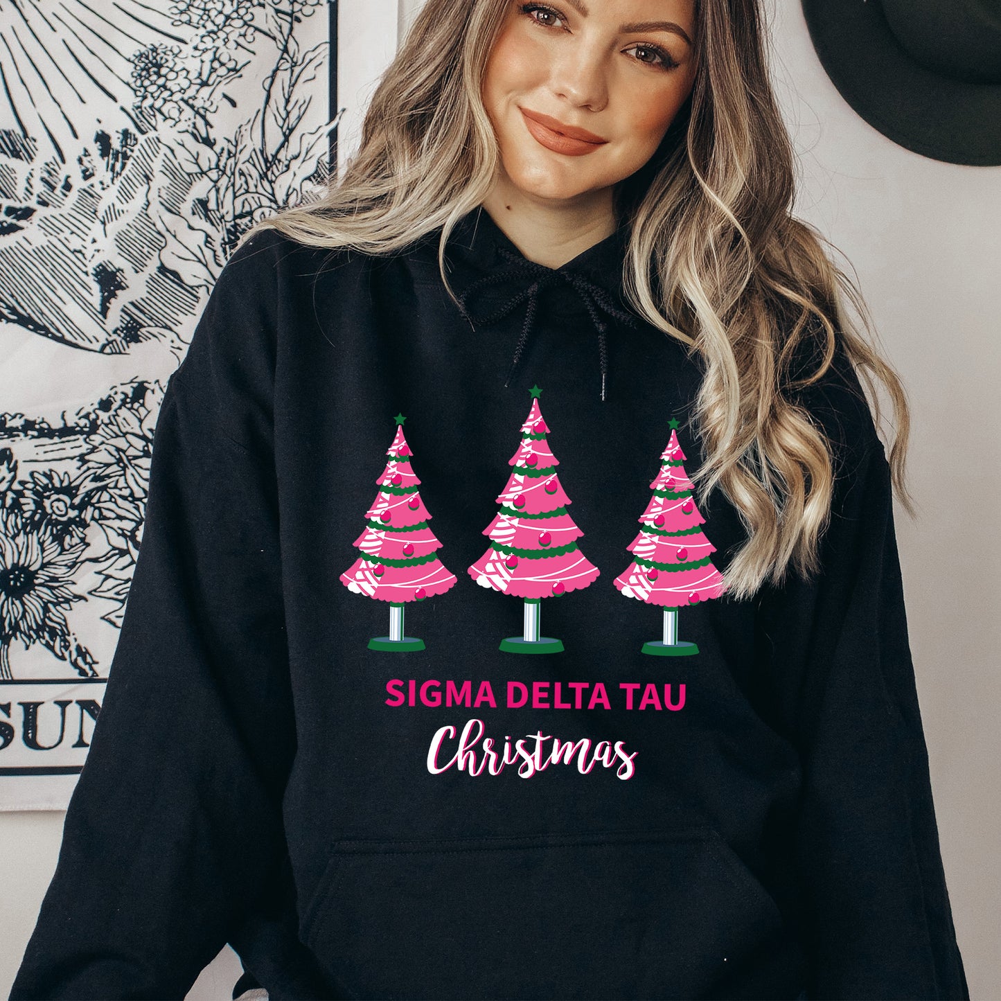 a woman wearing a black hoodie with pink christmas trees on it