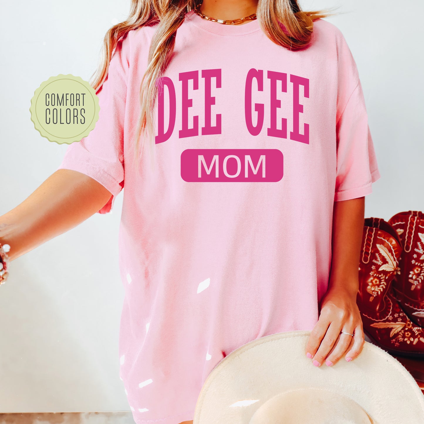 a woman wearing a pink shirt that says dee gee mom