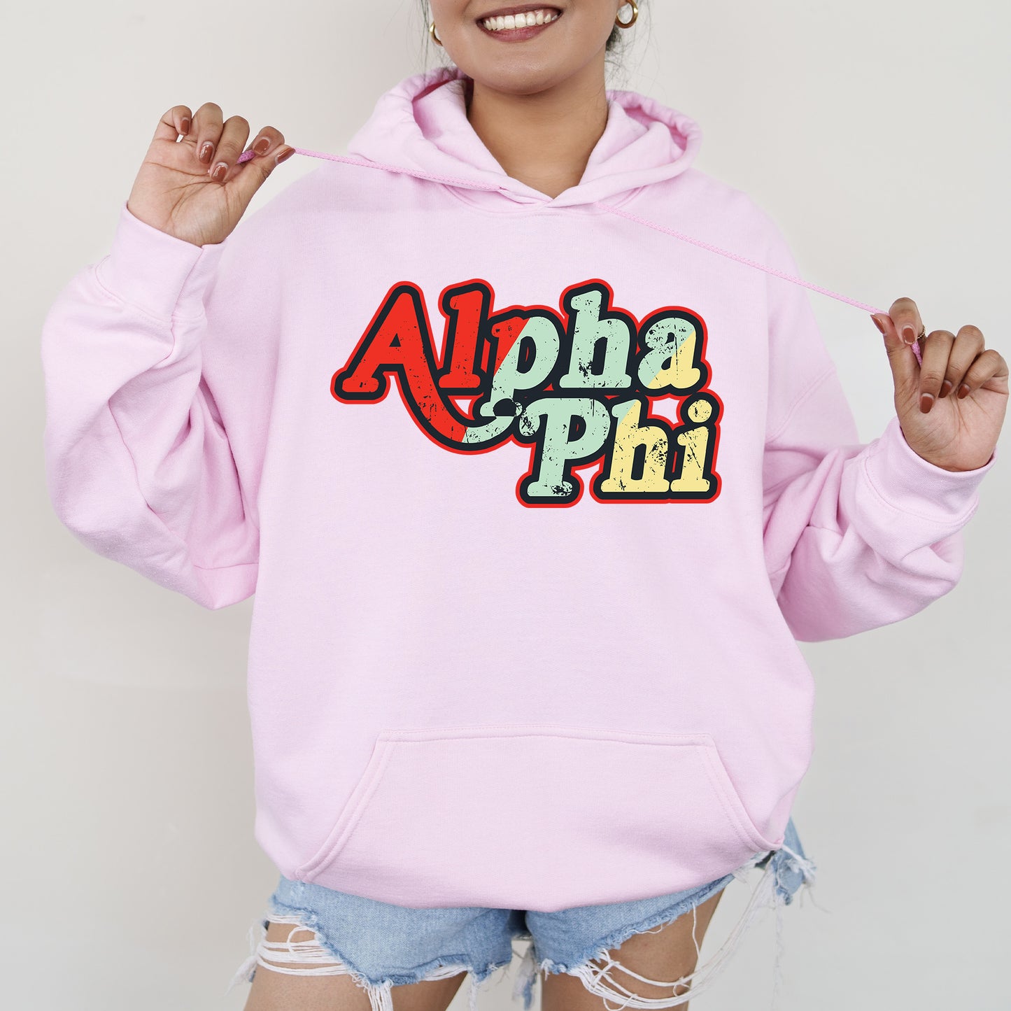 a woman wearing a pink hoodie with the word aloha phi on it