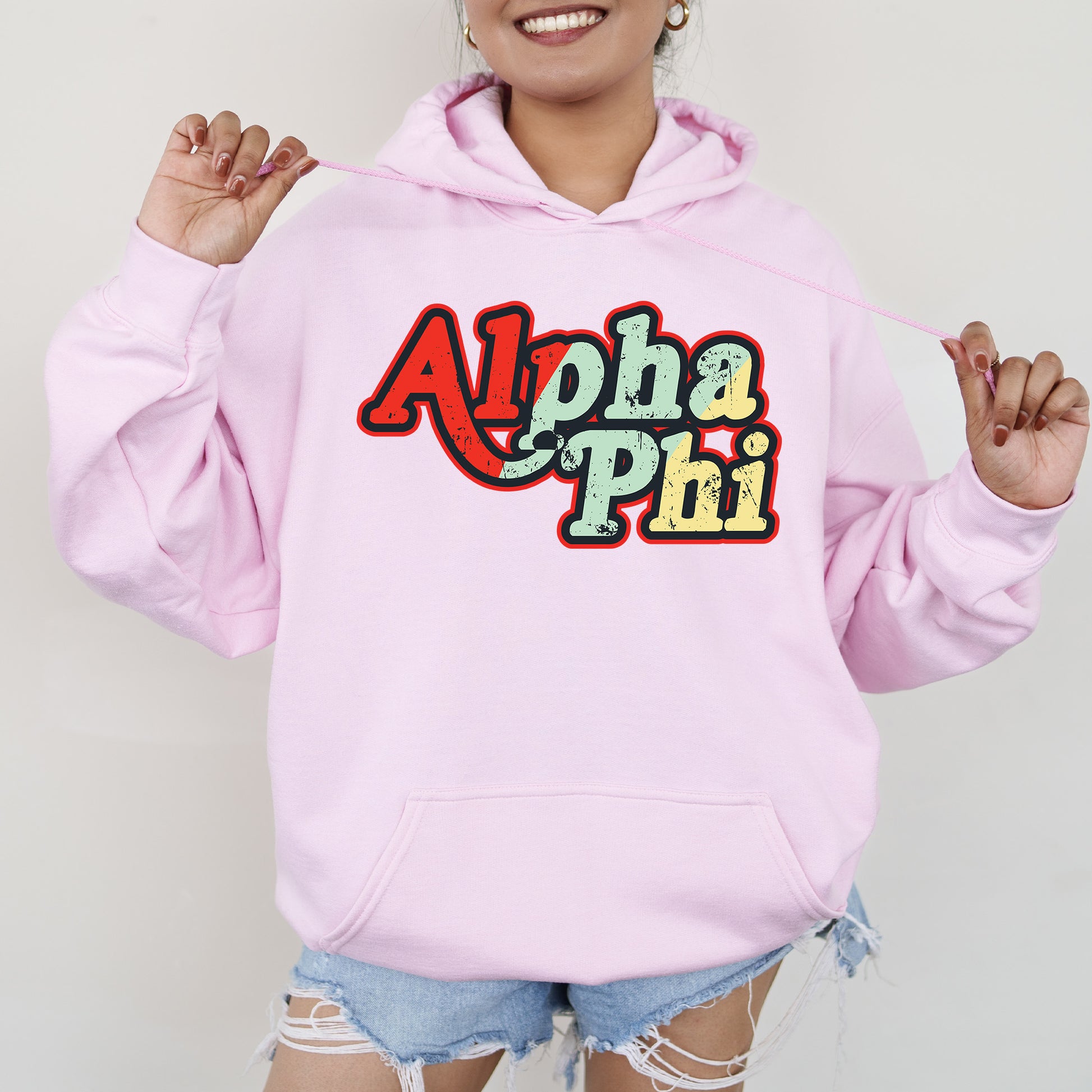 a woman wearing a pink hoodie with the word aloha phi on it