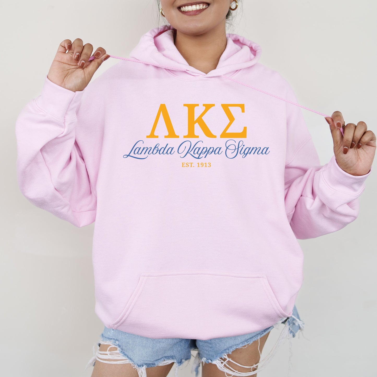 a woman wearing a pink hoodie and ripped shorts