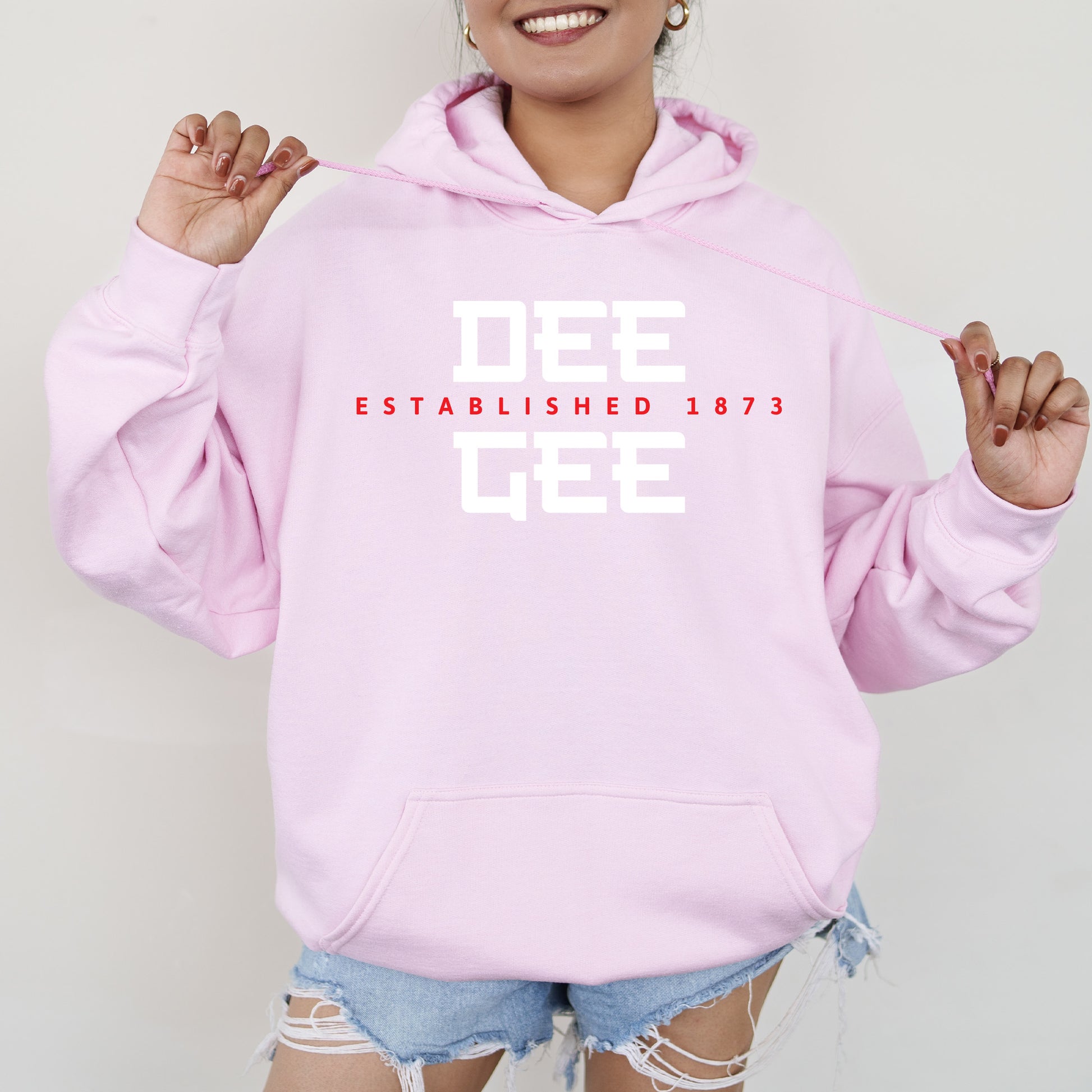 a woman wearing a pink sweatshirt and ripped shorts