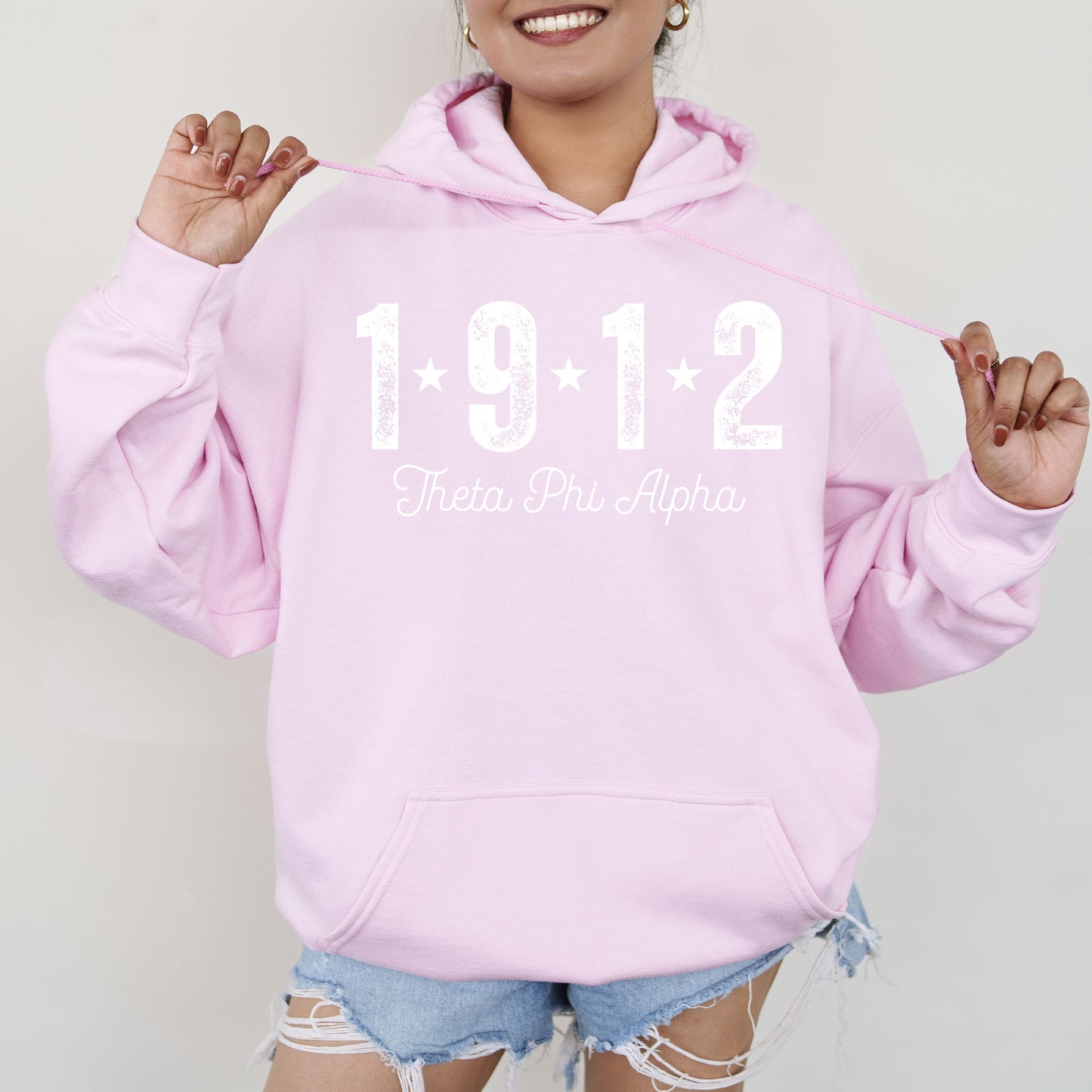 a woman wearing a pink hoodie with the number 1911 printed on it