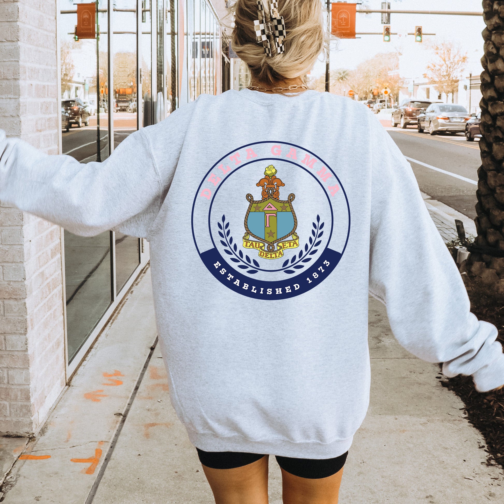 a woman walking down a sidewalk wearing a sweatshirt