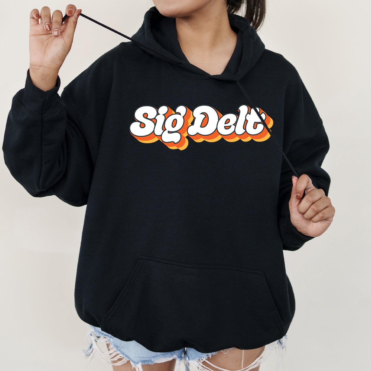 a woman wearing a black hoodie with a stick sticking out of her mouth