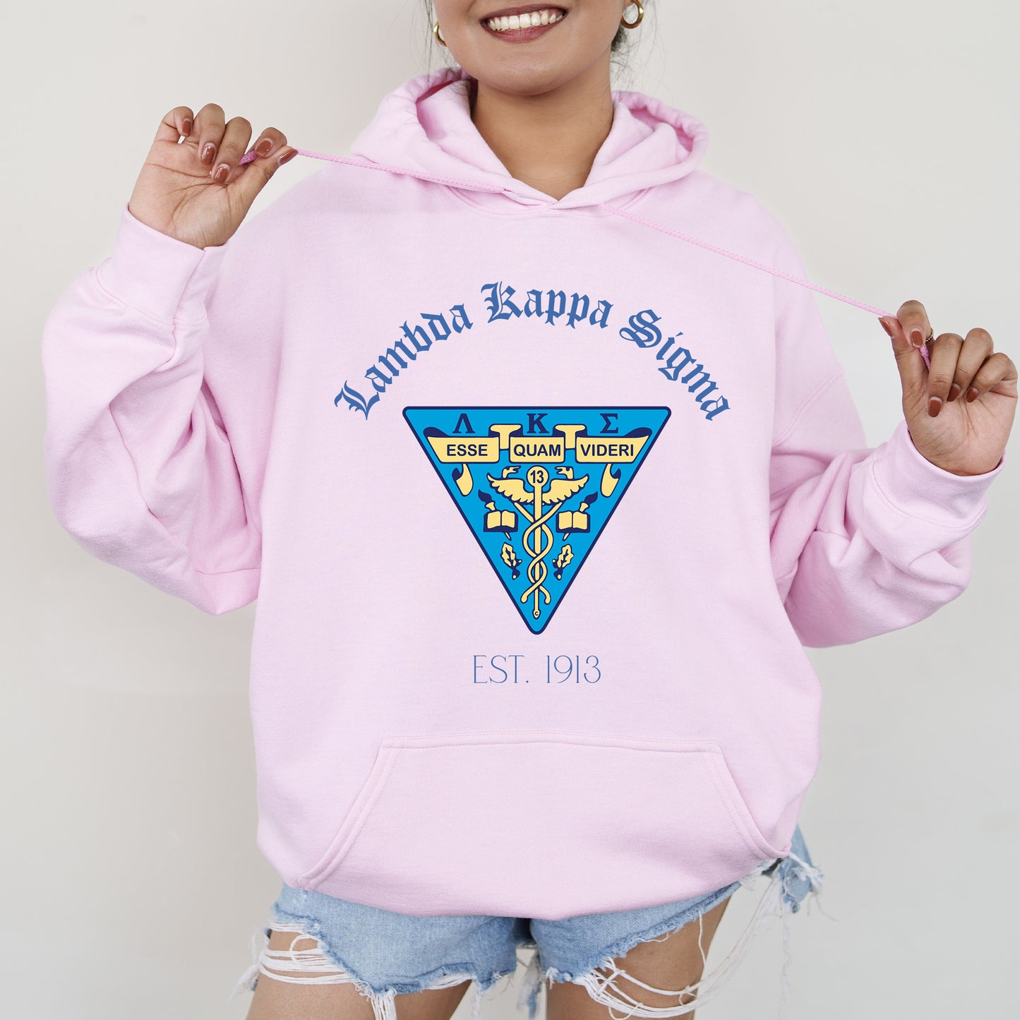 a woman wearing a pink hoodie and ripped shorts