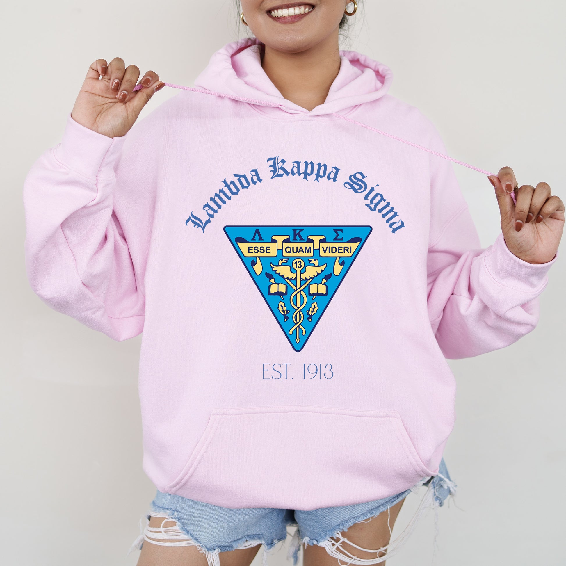 a woman wearing a pink hoodie and ripped shorts