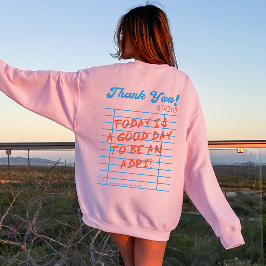 a woman wearing a pink sweatshirt with writing on it