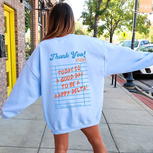 a woman in a blue sweatshirt is walking down the sidewalk