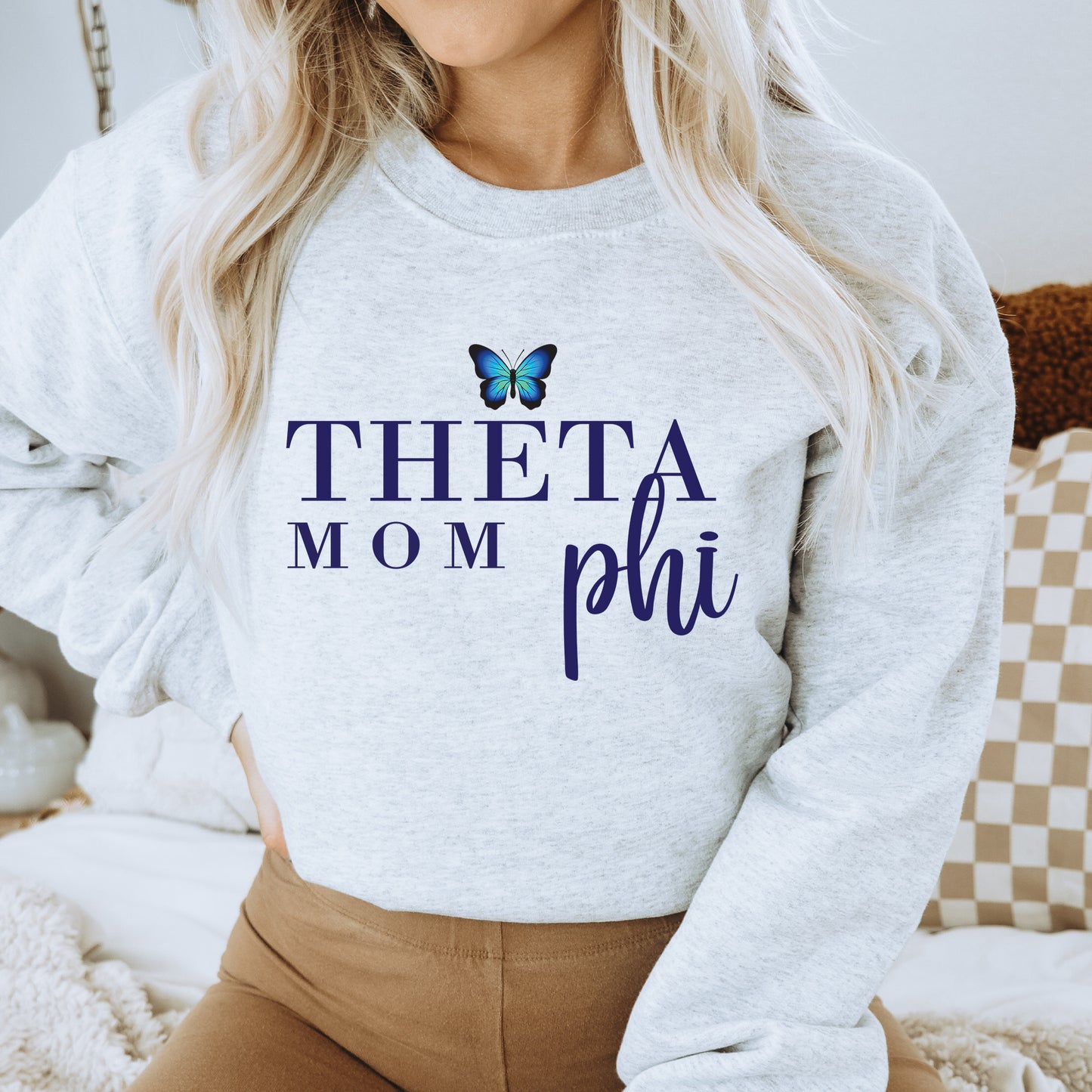 a woman wearing a sweatshirt that says thea mom phi