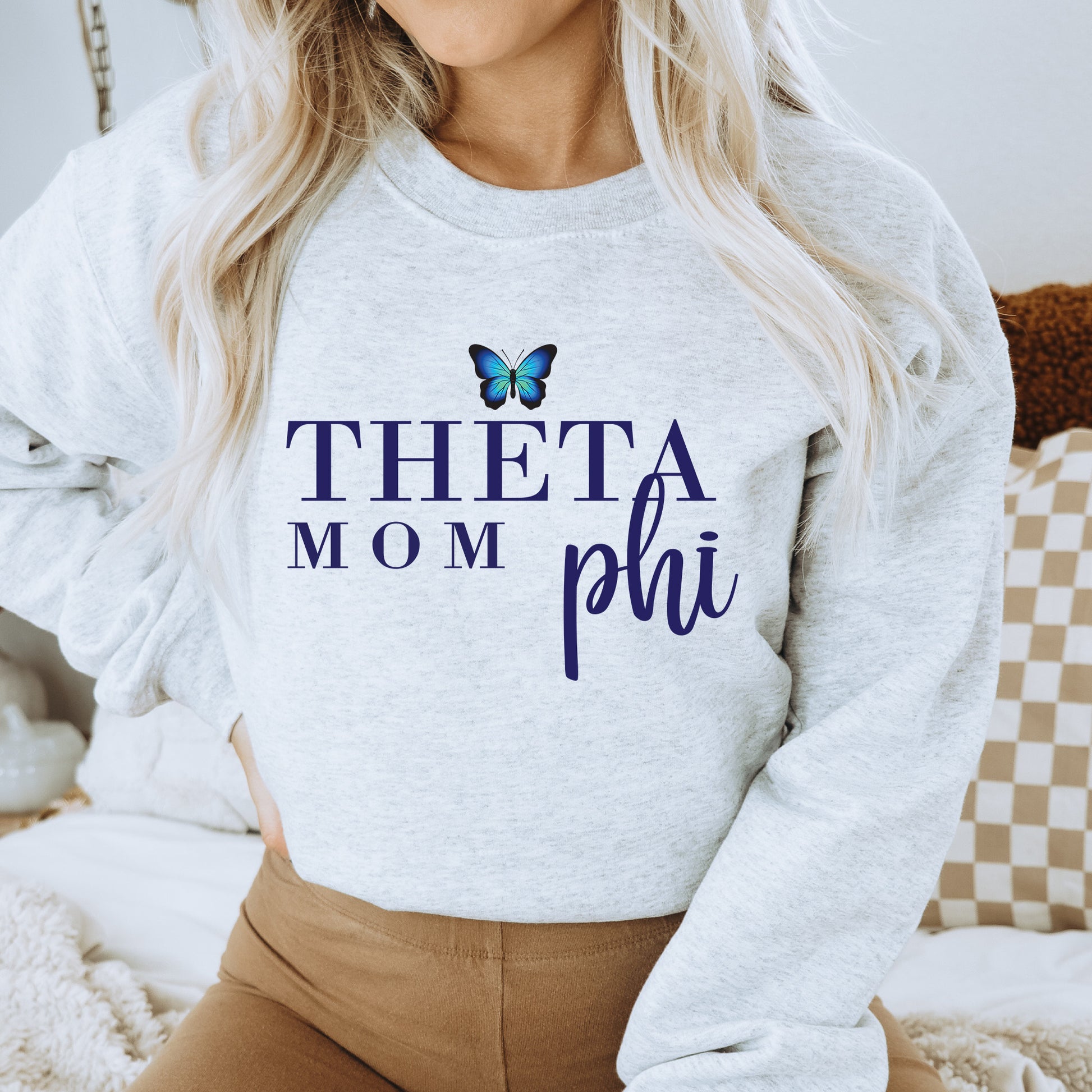 a woman wearing a sweatshirt that says thea mom phi