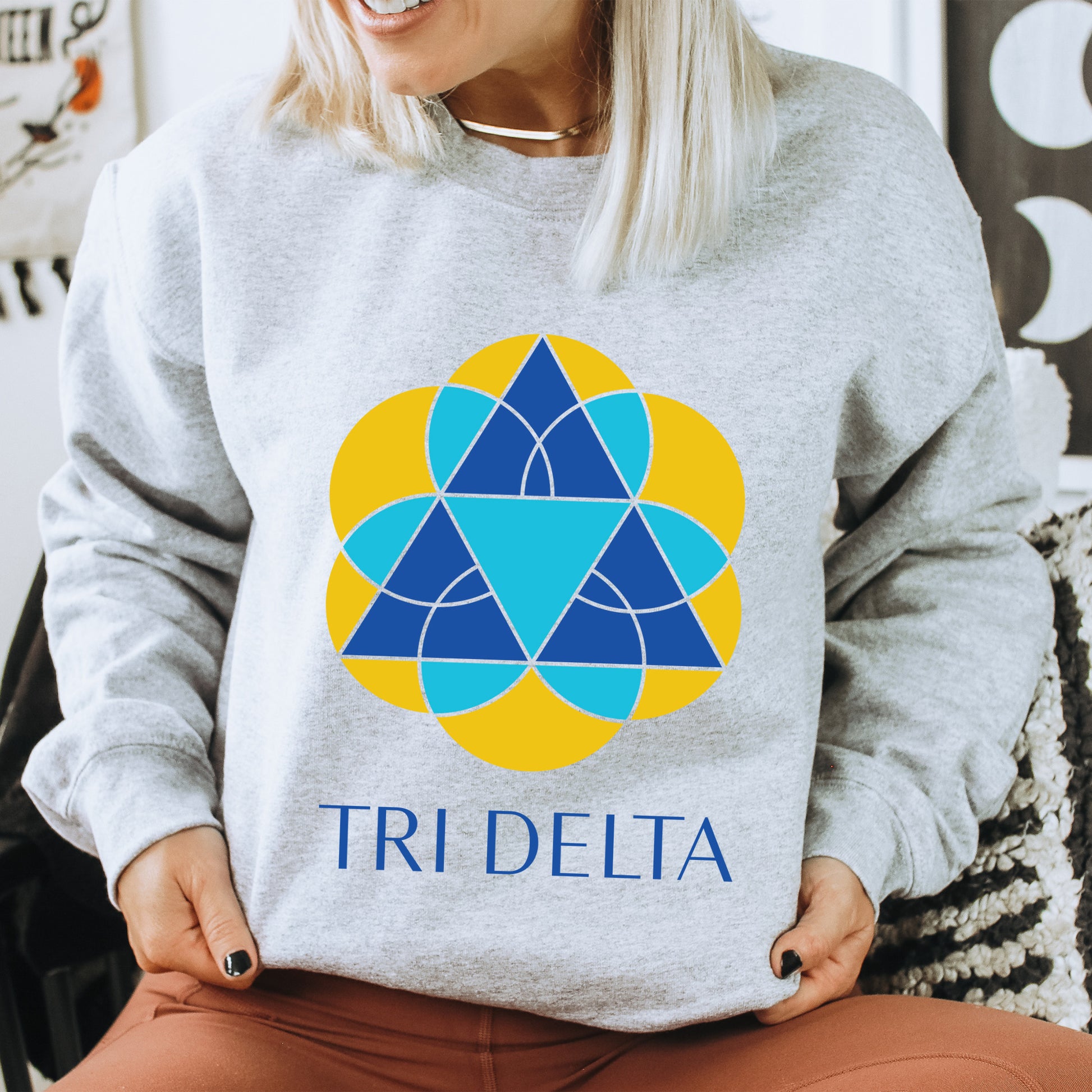 a woman sitting in a chair wearing a sweatshirt with a tri delta logo on it